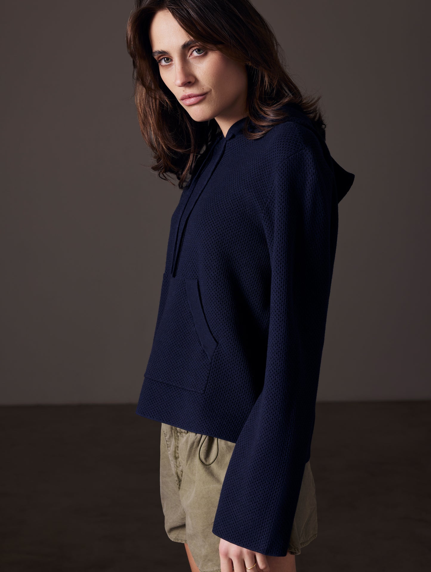 Side profile view of woman wearing Baja Mesh Sweater in Total Eclipse dark blue from AETHER Apparel.