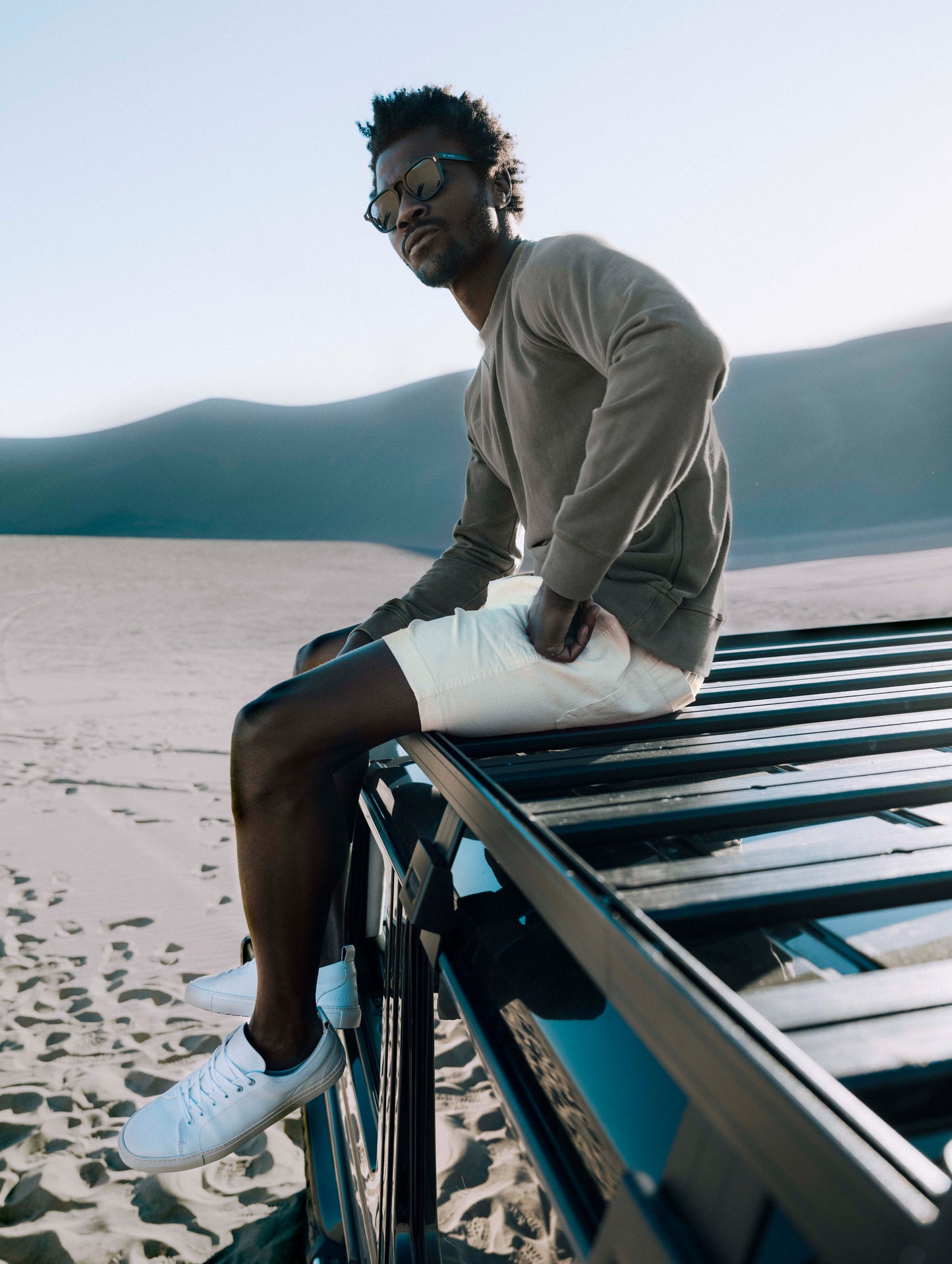 Outdoor lifestyle image of man sitting on roof of truck wearing Norton Cotton Ripstop Short in Bone white from AETHER Apparel.