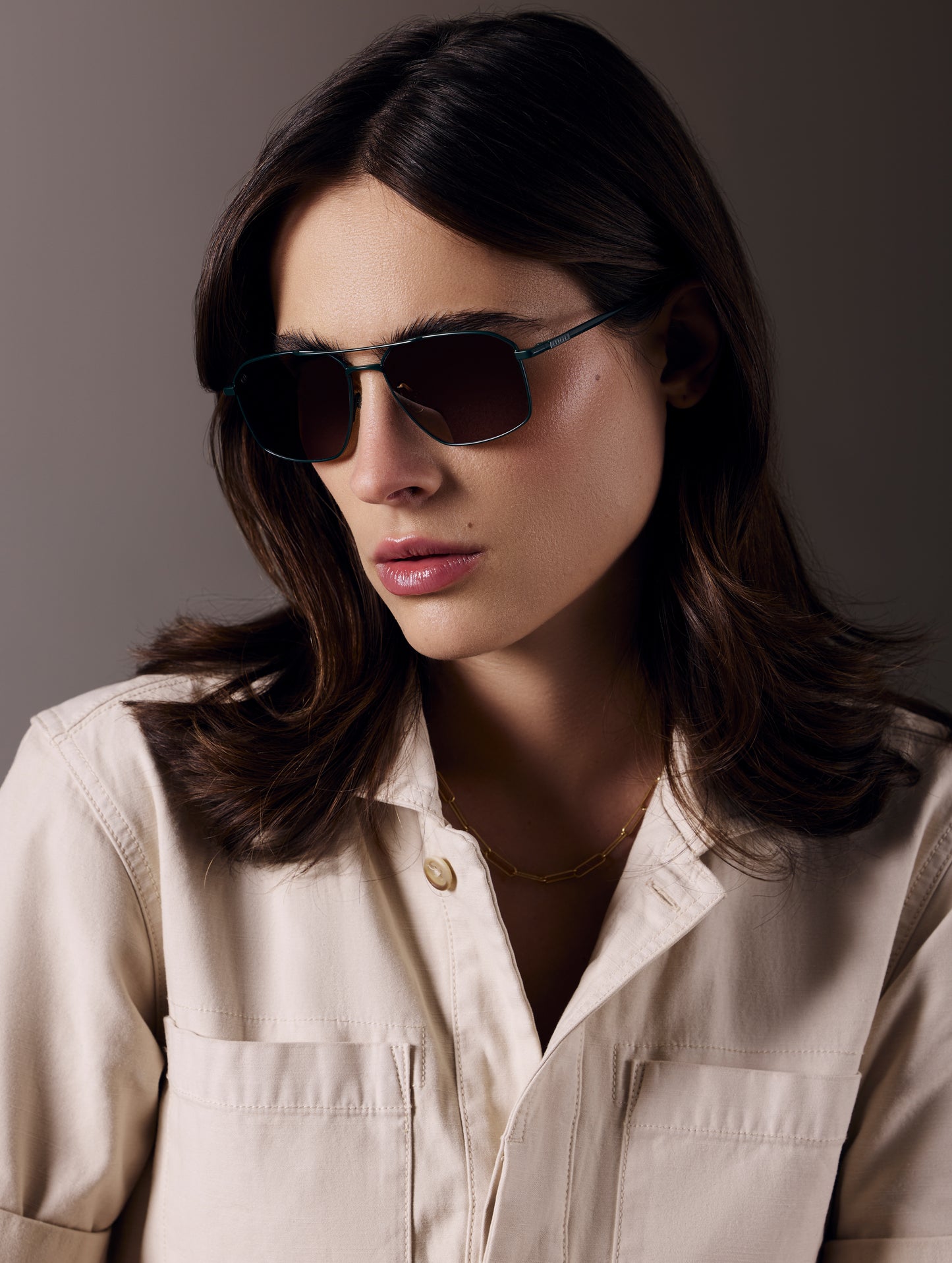 Front angled view of woman wearing Arches Sunglass in Green with Brown Lens from AETHER Apparel.