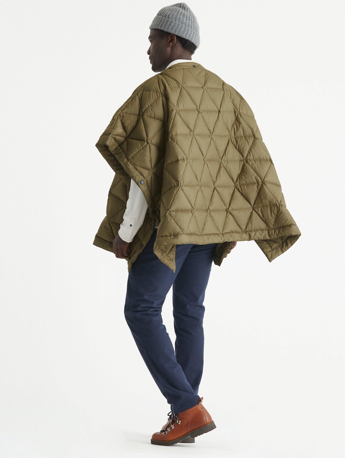 Rear 3/4 full-body view of man wearing Down Poncho in Command Green from AETHER Apparel.