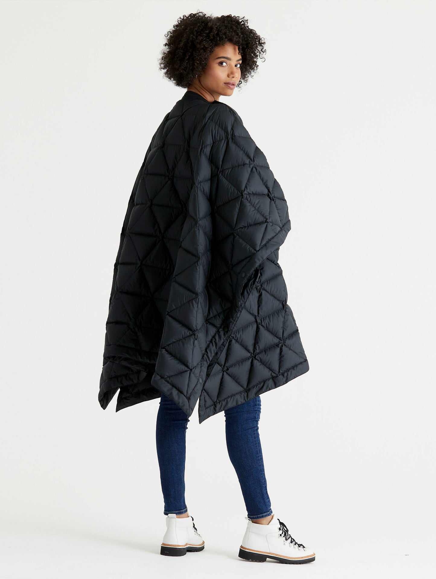 Rear 3/4 full-body view of woman wearing Down Poncho in Onyx Black from AETHER Apparel.