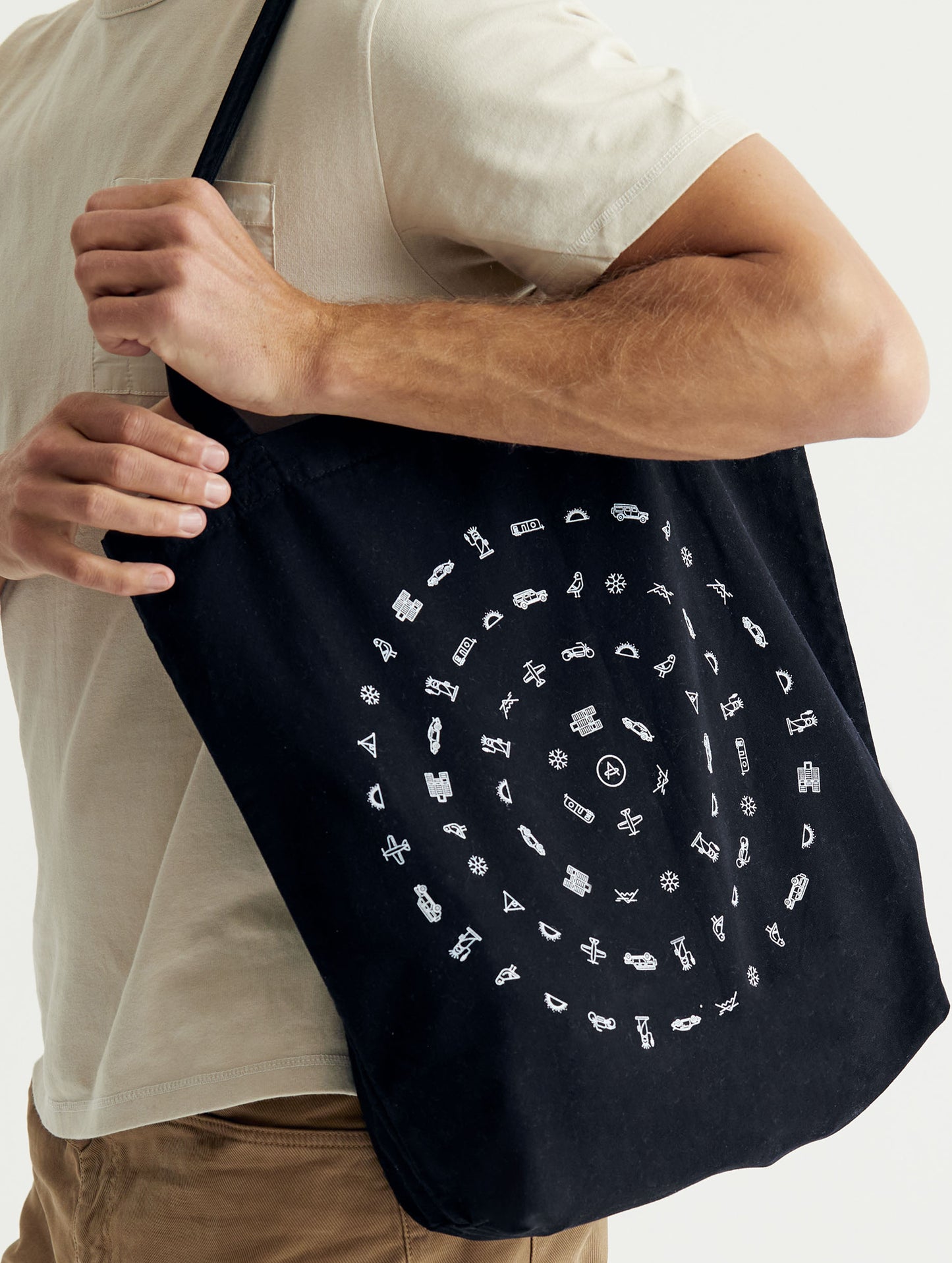 Front angled view of man carrying Lifestyle Canvas Tote in Onyx Black from AETHER Apparel.
