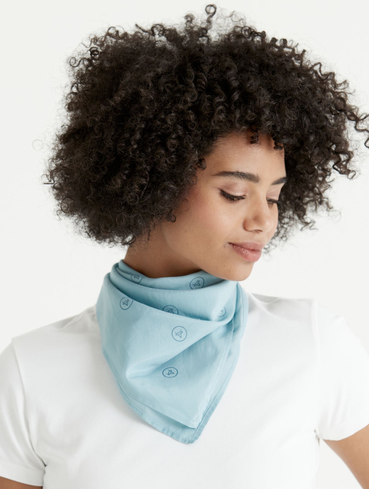 Front angled view of woman wearing Logo Bandana in Mist Blue from AETHER Apparel around neck.