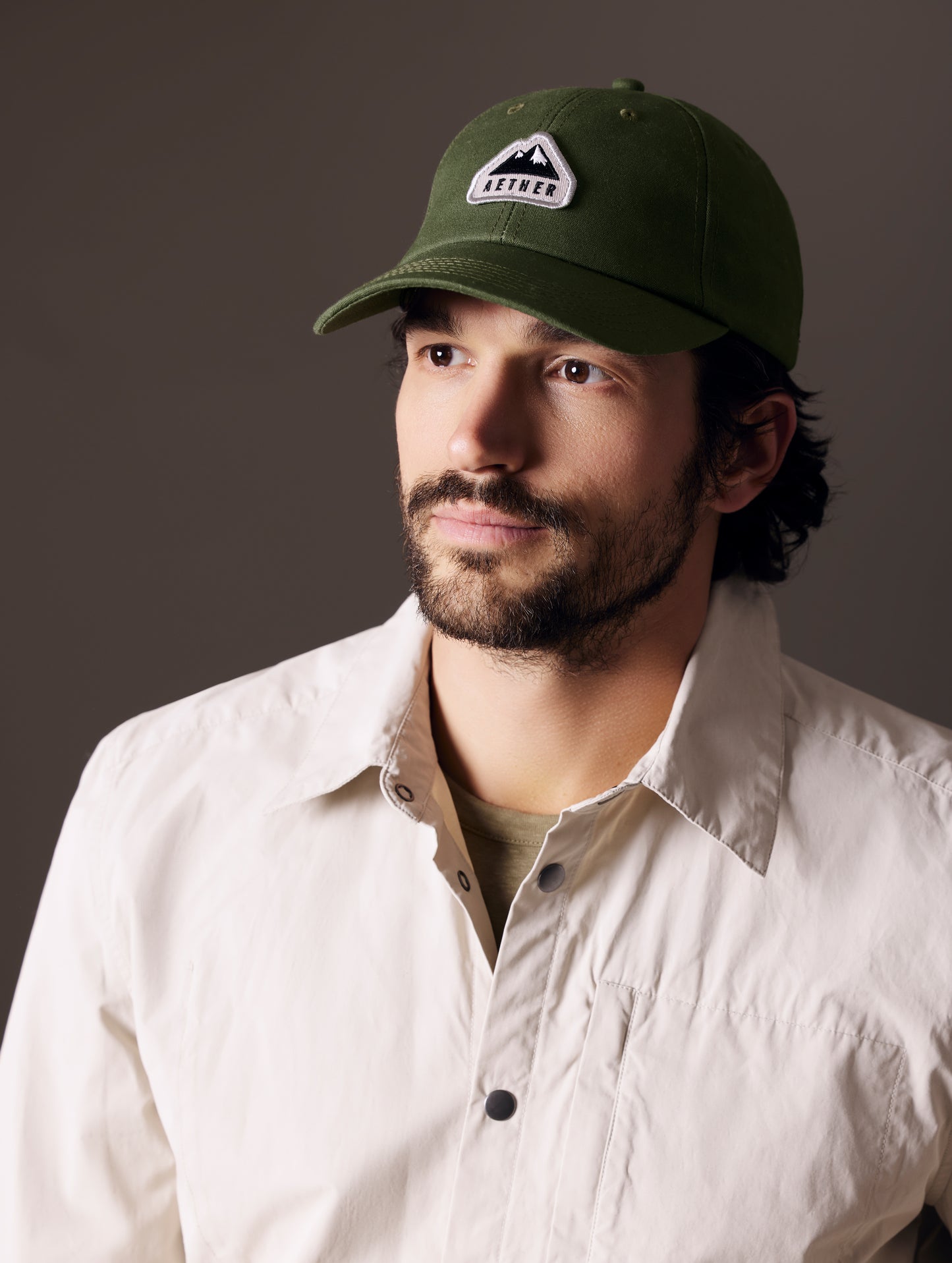 Front angled view of man wearing AETHER Mountain Hat in Army Green from AETHER Apparel.