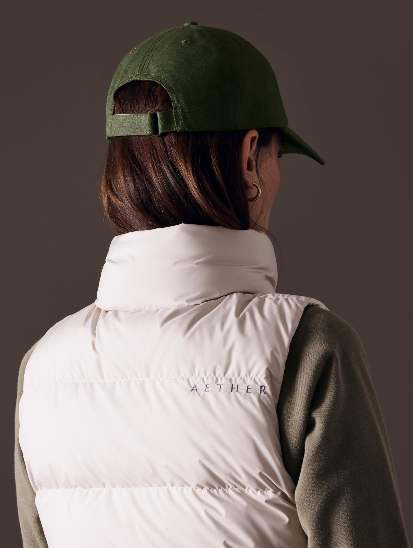 Rear angled view of woman wearing AETHER Mountain Hat in Army Green from AETHER Apparel.