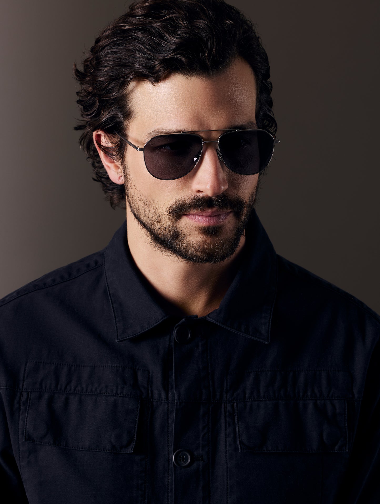 Front right 3/4 view of man wearing Bryce Sunglass in Brushed Silver titanium with Grey Lens from AETHER Apparel.
