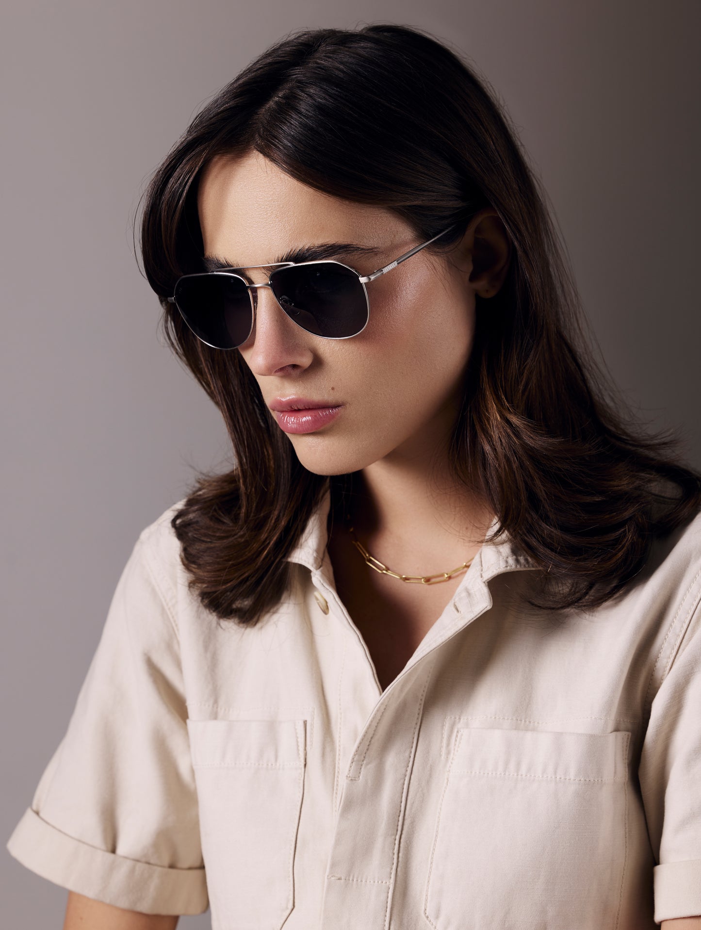 Front 3/4 view of woman wearing Bryce Sunglass in Brushed Silver titanium with Grey Lens from AETHER Apparel.