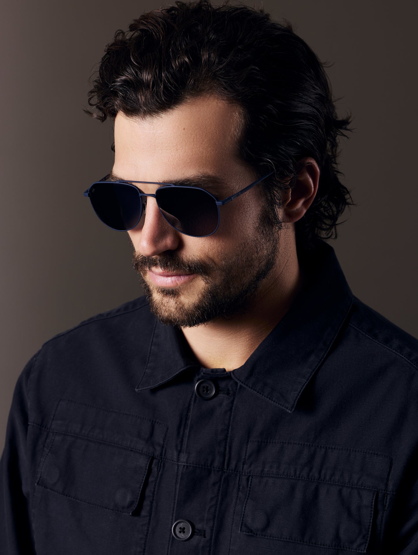 Front 3/4 view of man wearing Bryce Sunglass in black titanium with Blue Lens from AETHER Apparel.
