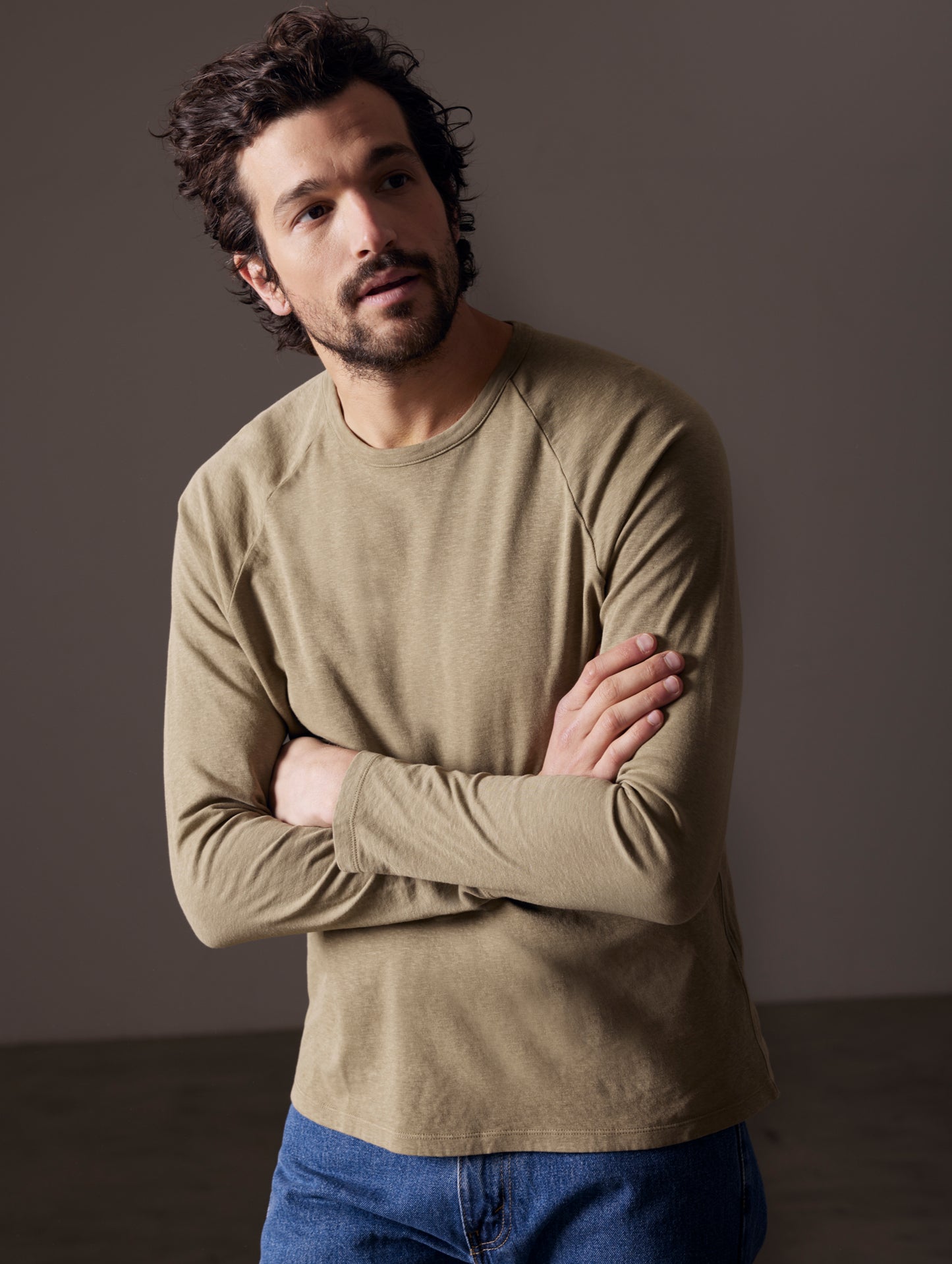 Front body view of man with arms crossed wearing Buckhorn Cotton Raglan Long-Sleeve Tee in Mineral Green from AETHER Apparel.