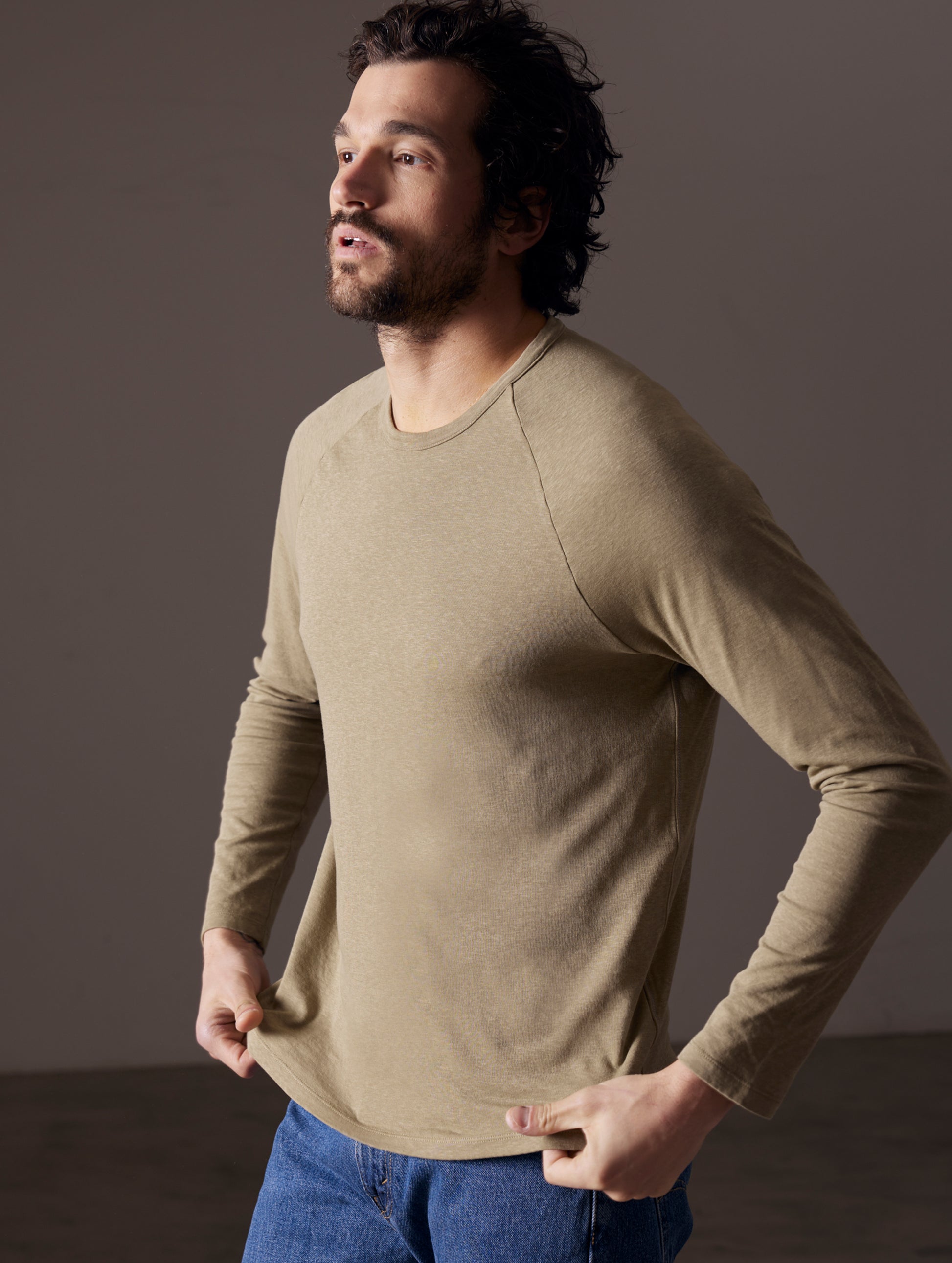Front angled body view of man wearing Buckhorn Cotton Raglan Long-Sleeve Tee in Mineral Green from AETHER Apparel.
