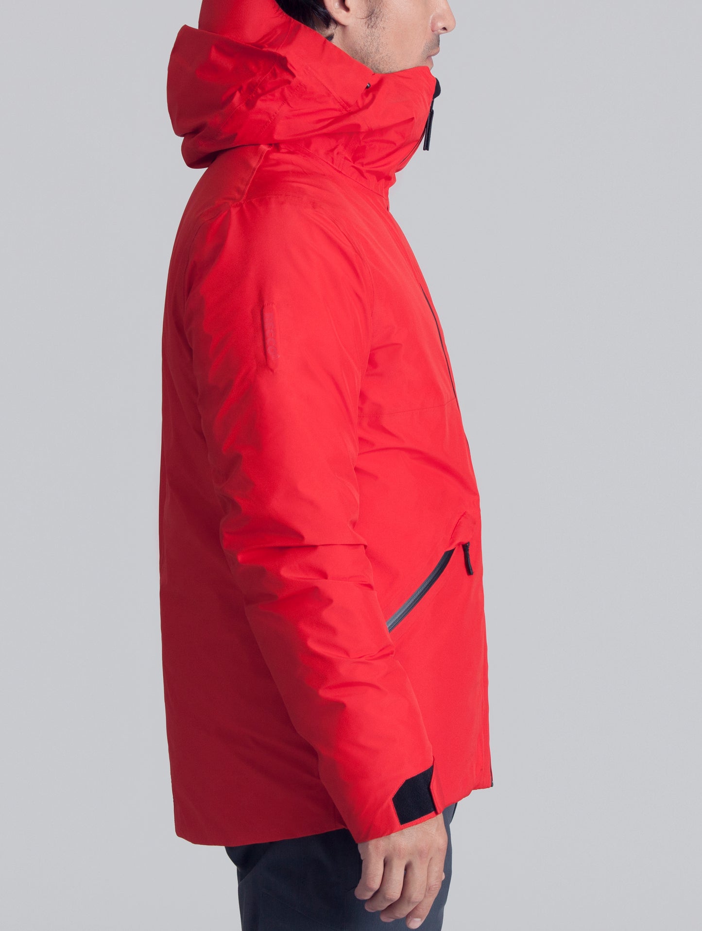 Right side view of man wearing red Crest Down Jacket from AETHER Apparel.