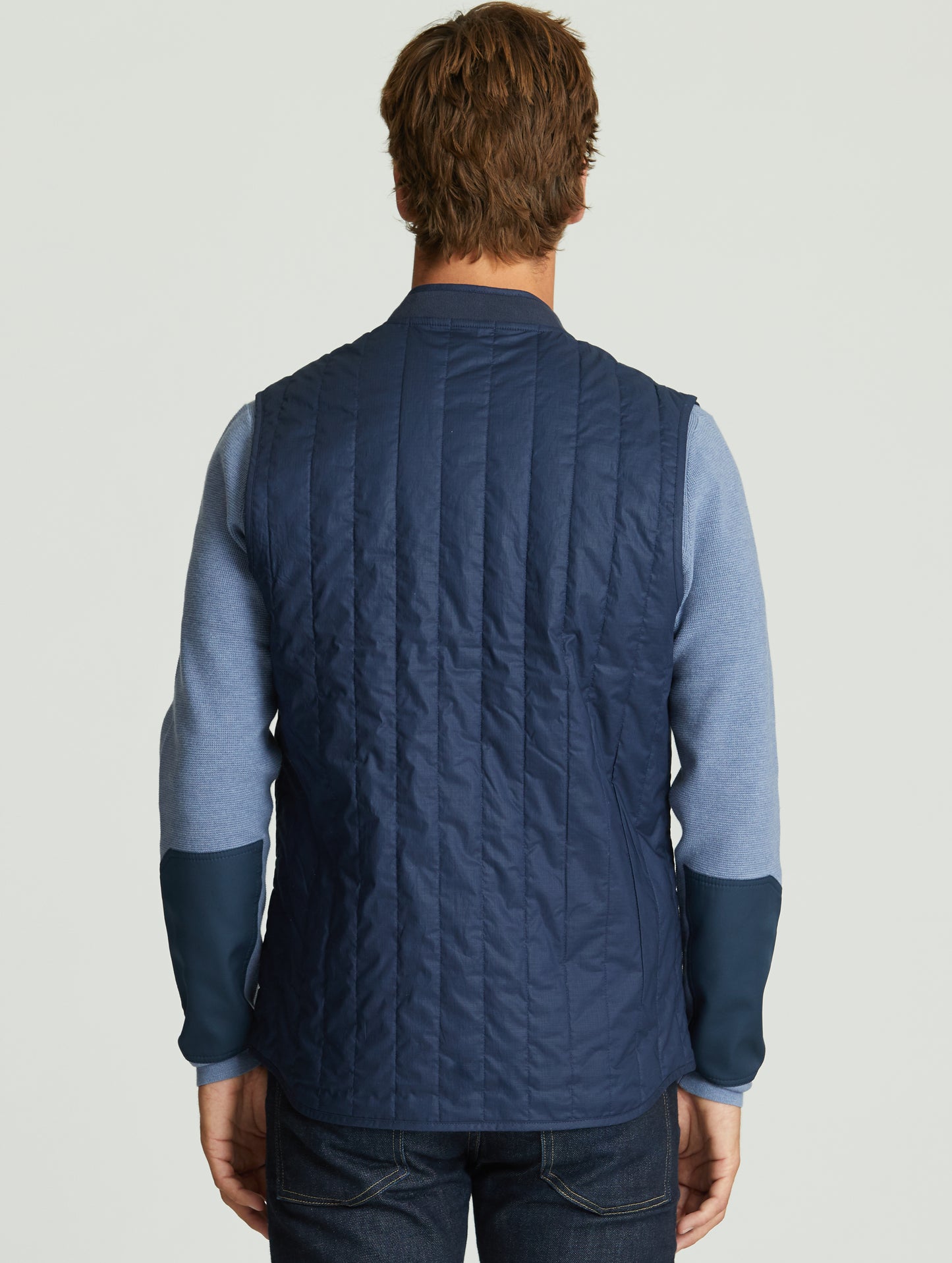 Back view of man wearing dark blue Griffith Vest from AETHER Apparel.