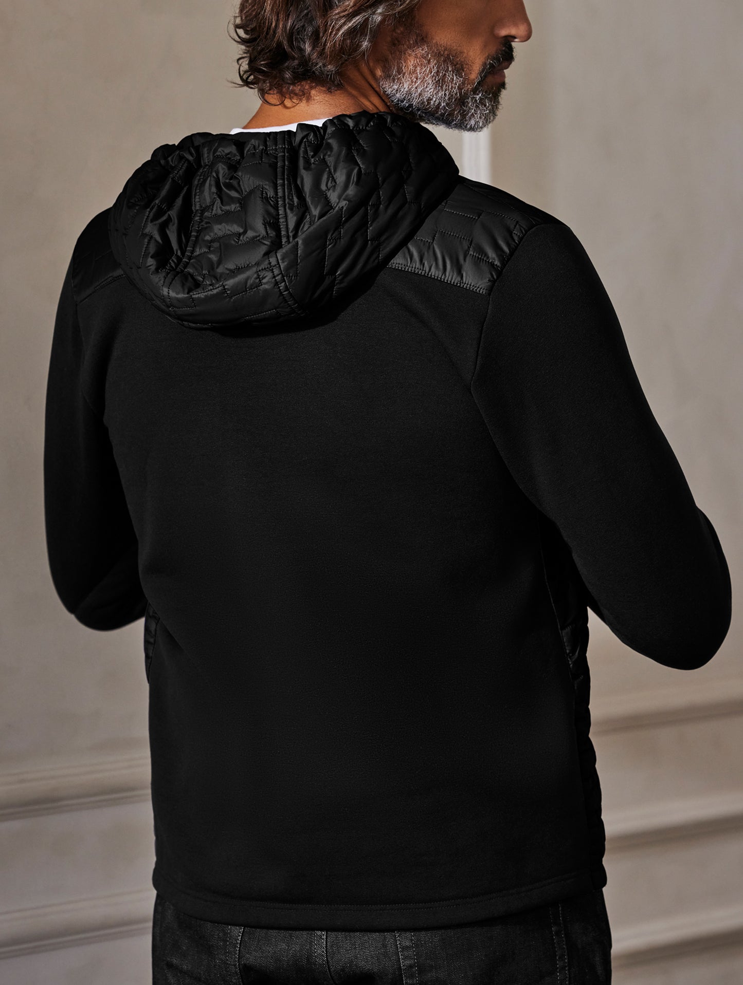Back view of man wearing Hybrid Tech Hoodie from AETHER Apparel.