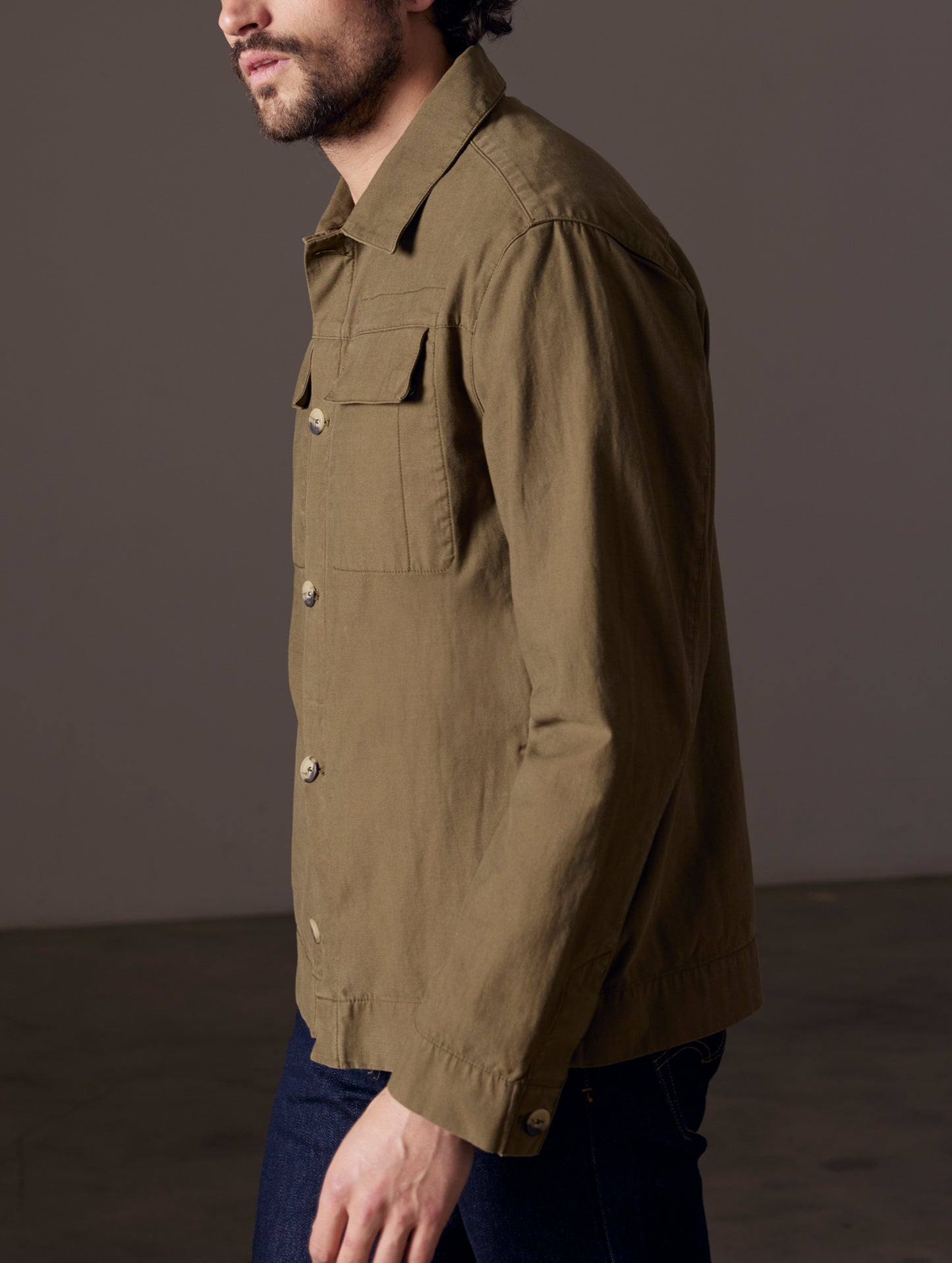Side profile body view of man wearing Mesa Jacket in Command Green from AETHER Apparel.