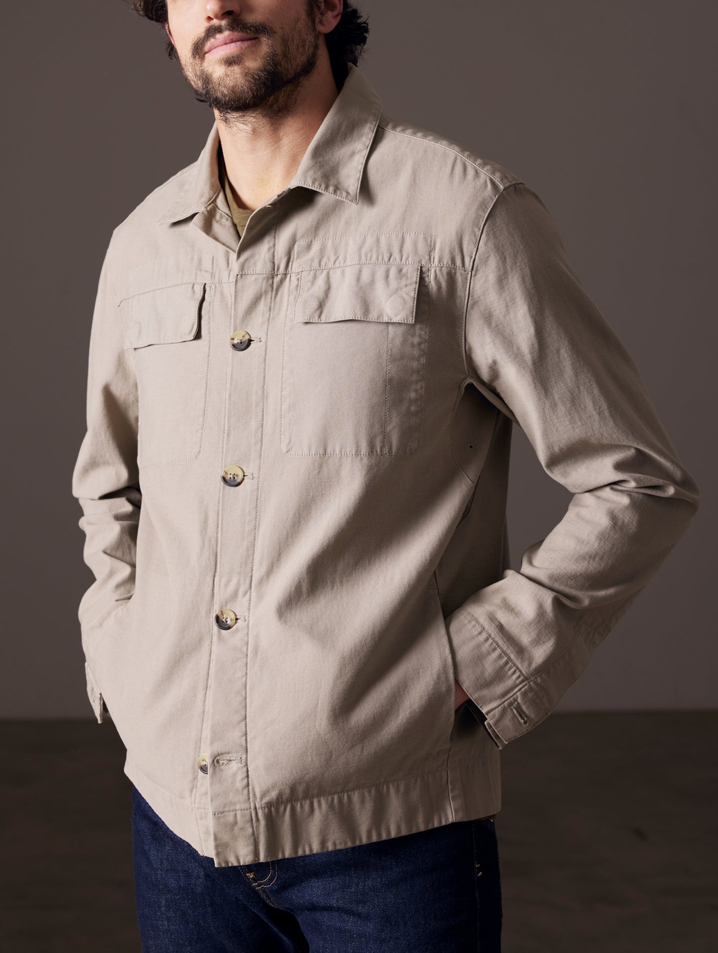 Front 3/4 body view of man with hands in coat pockets wearing Mesa Jacket in Laurel Grey from AETHER Apparel.