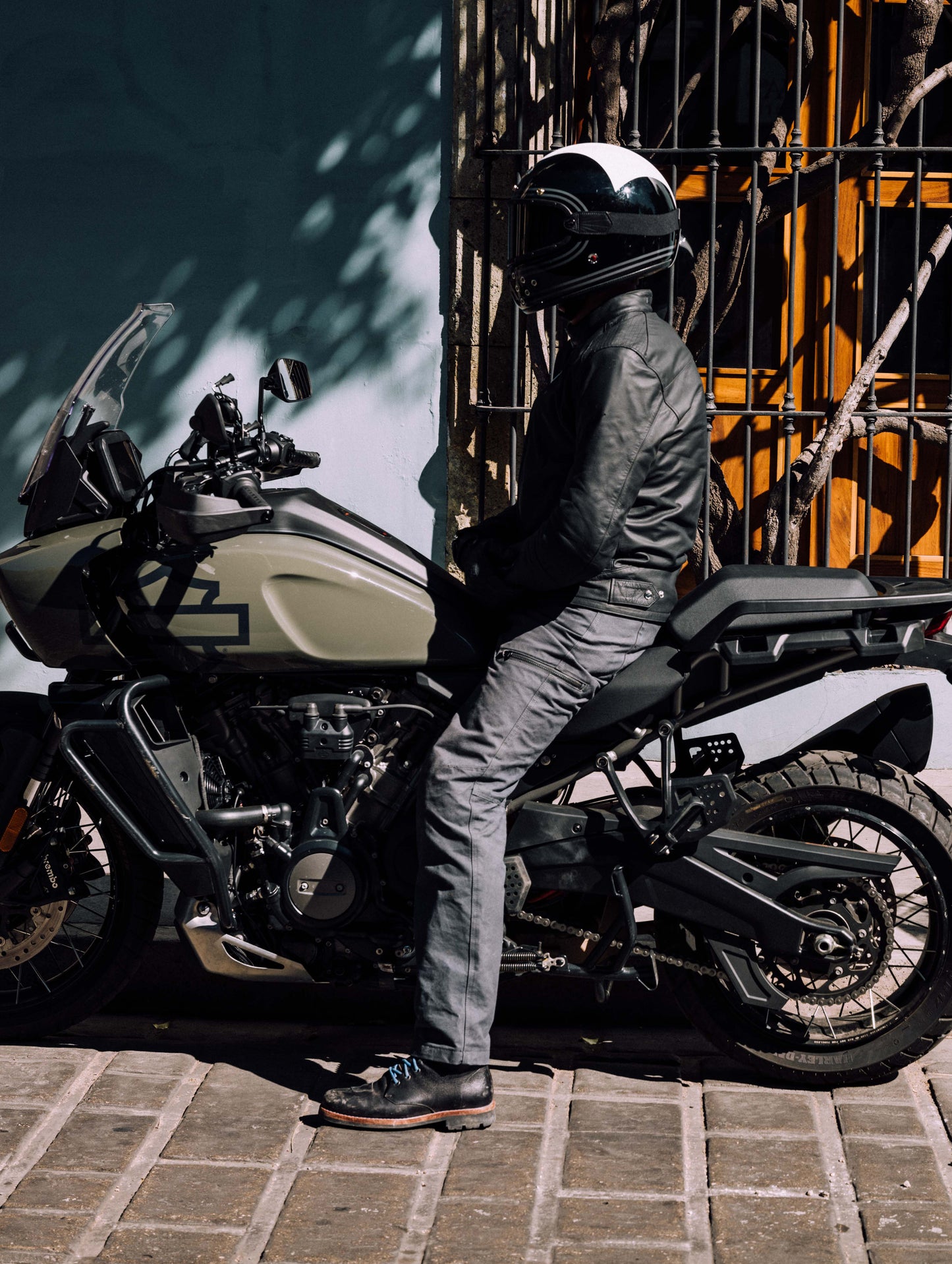 Outdoor lifestyle image of man sitting on Harley-Davidson adventure motorcycle wearing AETHER Moto Boot in Jet Black from AETHER Apparel.