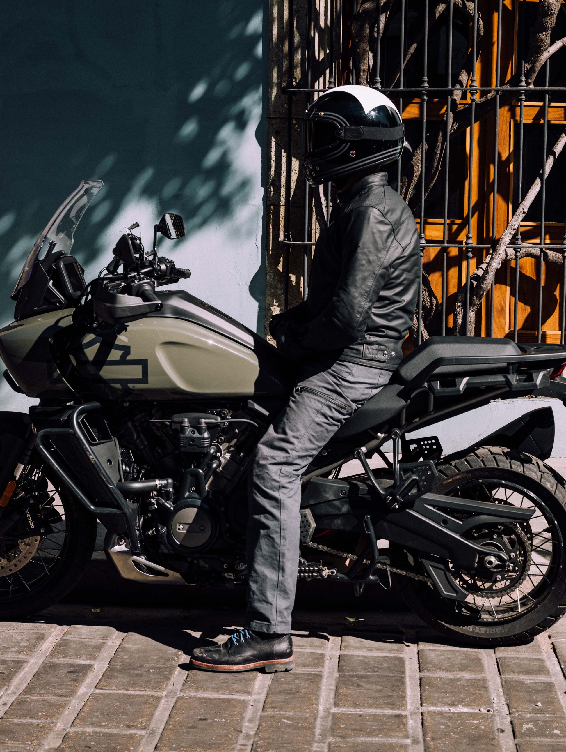 Outdoor lifestyle image of man sitting on Harley-Davidson adventure motorcycle wearing AETHER Moto Boot in Jet Black from AETHER Apparel.