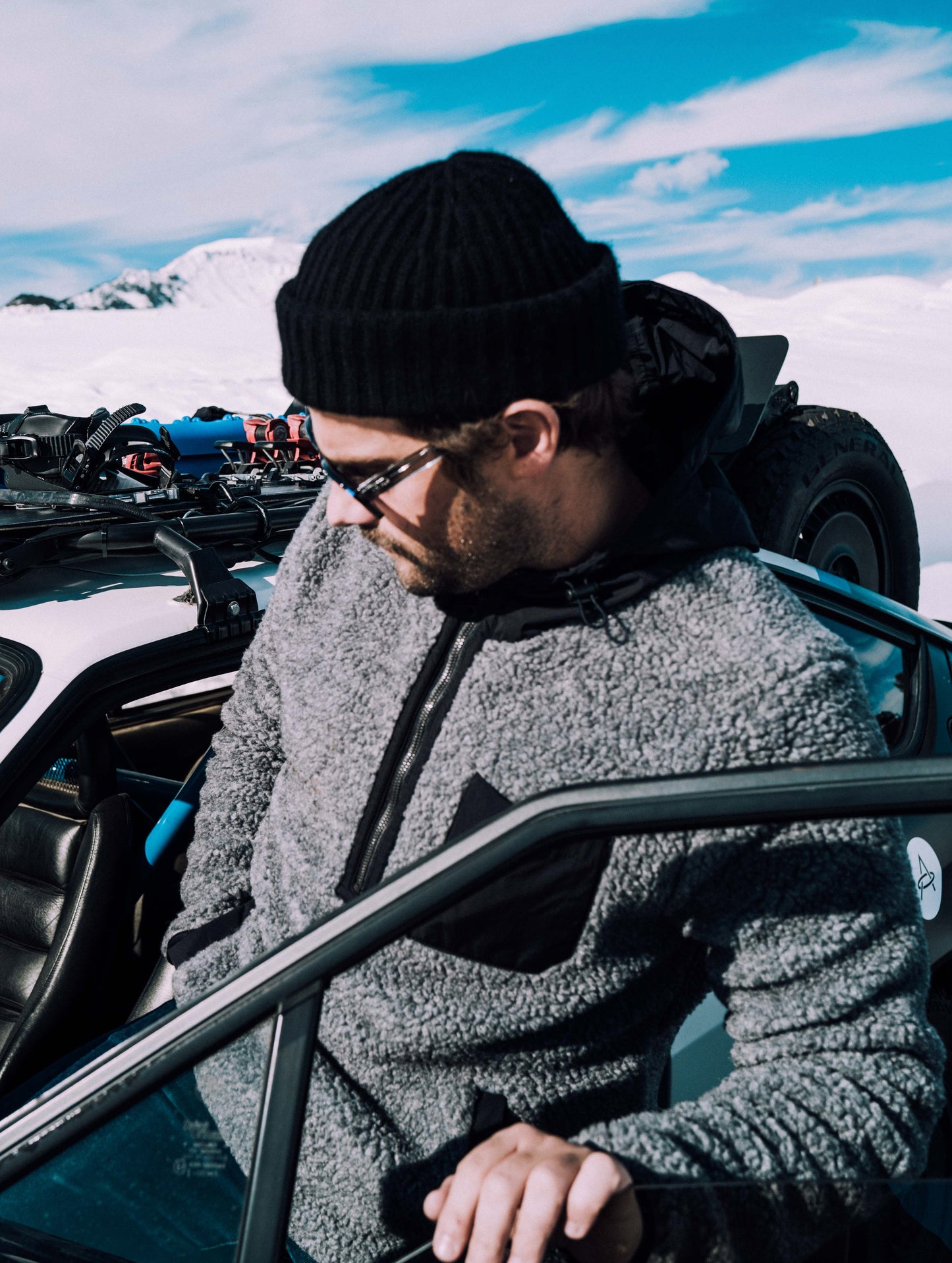 Outdoor lifestye image of man getting into car wearing Narrows Pullover in Rocket Grey from AETHER Apparel.