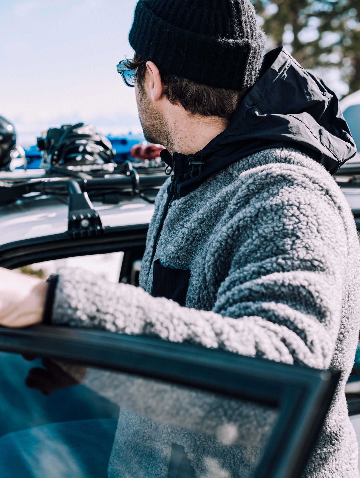 Outdoor lifestyle image of man with arm on car door wearing Narrows Pullover in Rocket Grey from AETHER Apparel.