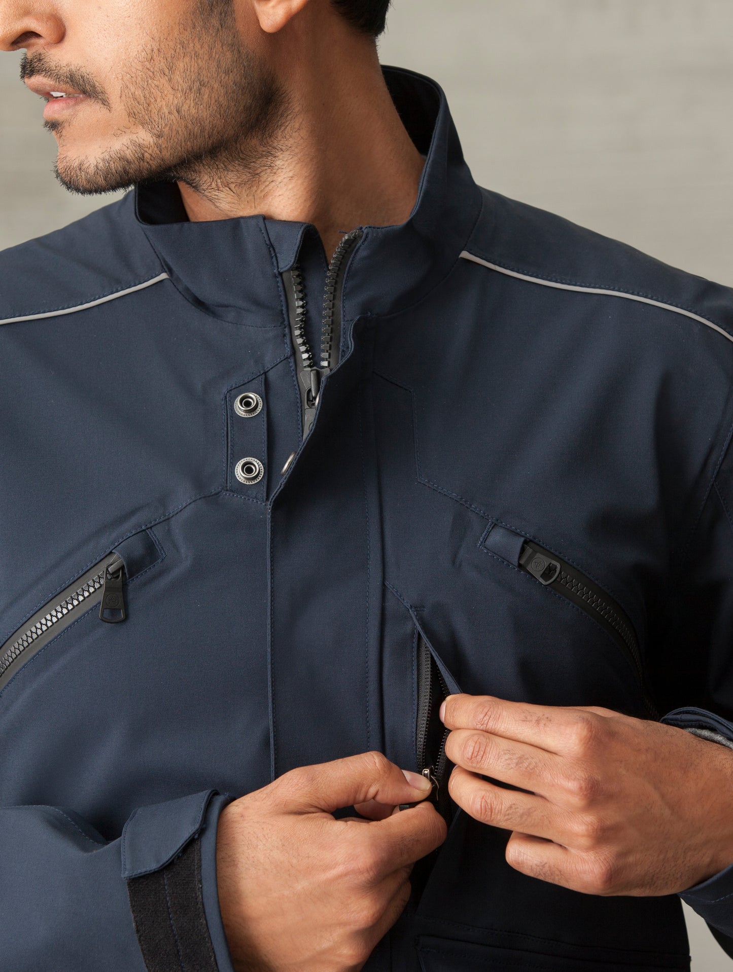 Man wearing blue Navigator Motorcycle Jacket from AETHER Apparel displaying front zippered pocket.