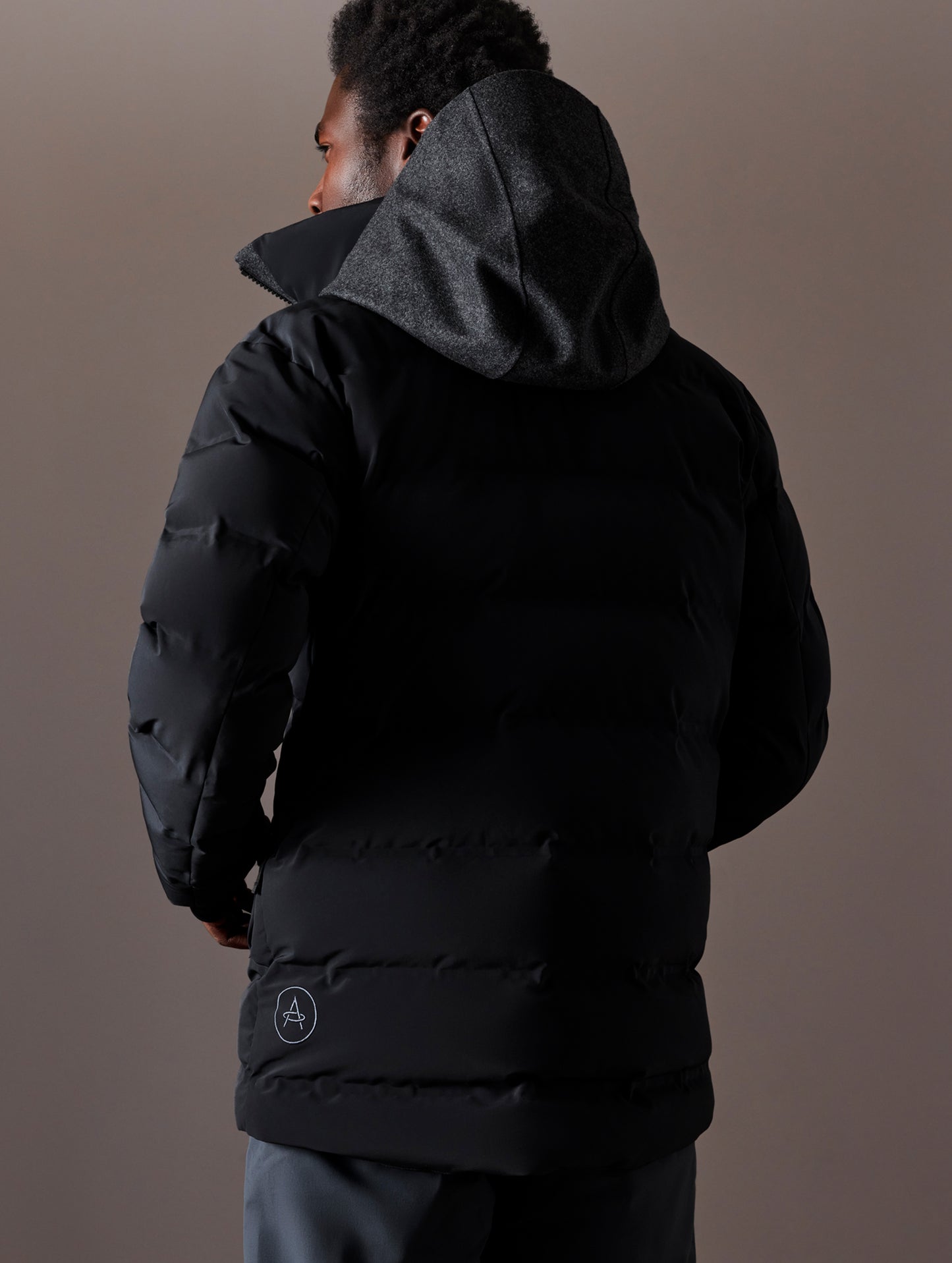 Rear 3/4 body view of man wearing Nordic Jacket in Jet Black from AETHER Apparel.