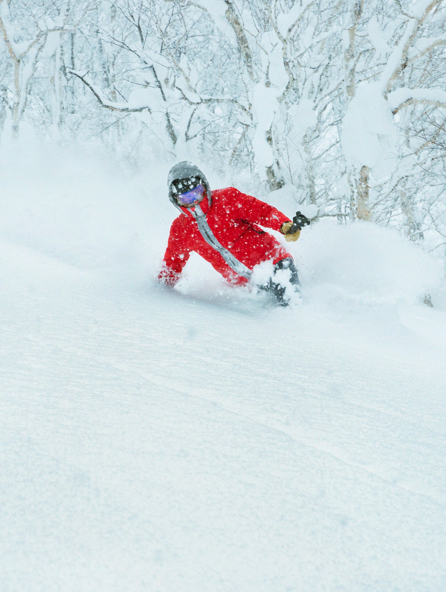 Outdoor lifestyle image of man skiing through powder wearing Nordic Jacket in Racing Red from AETHER Apparel.