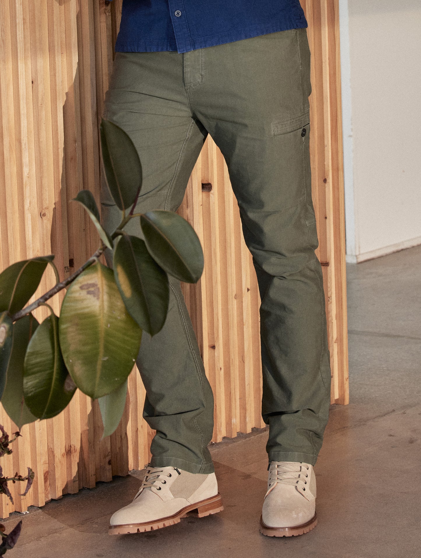 Lifestyle image of man leaning against wall wearing Ojai City Boot in Natural suede and canvas from AETHER Apparel.