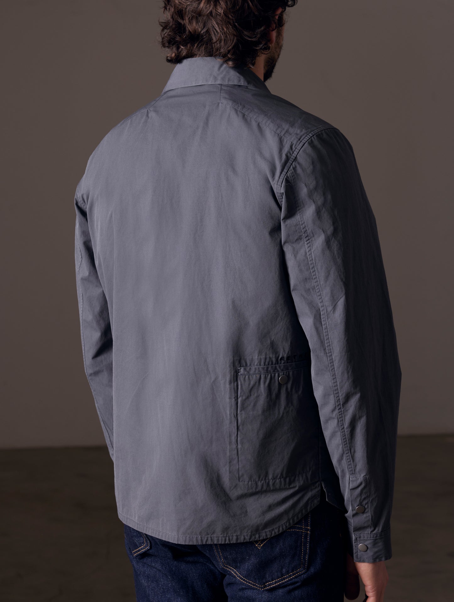 Rear 3/4 body view of man wearing Pine Shacket in Graphite from AETHER Apparel.