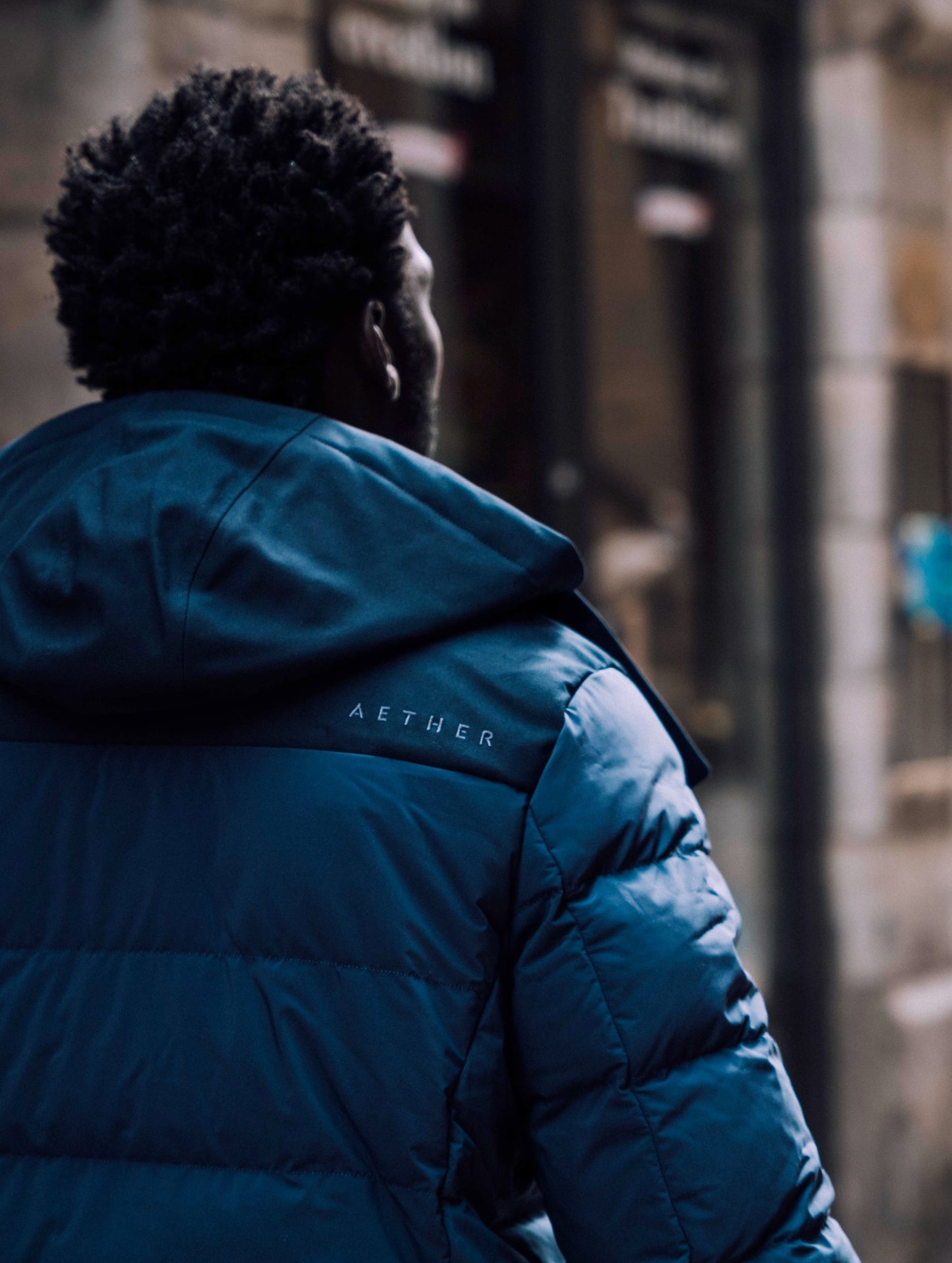 Outdoor lifestyle image of rear shoulder of man wearing Scott Parka in Nordic Navy blue from AETHER Apparel.