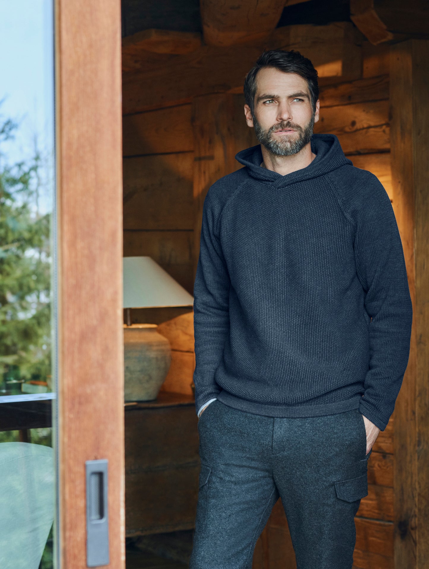 Full body view of man wearing dark blue Sierra Hooded Sweater from AETHER Apparel.