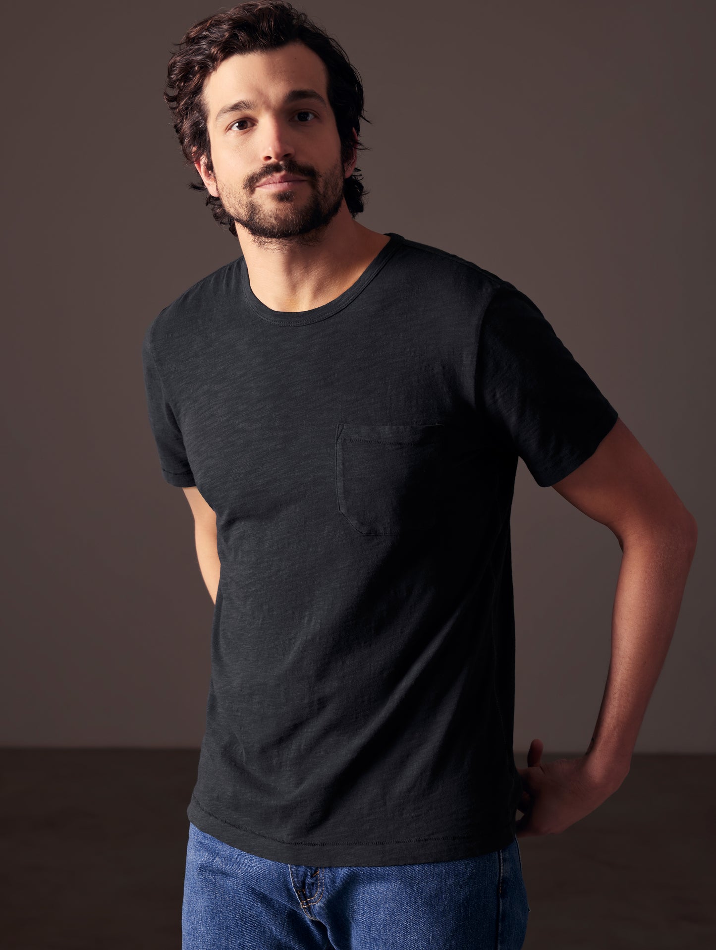 Front angled body view of man wearing Slub Pocket Tee in Onyx Black from AETHER Apparel.