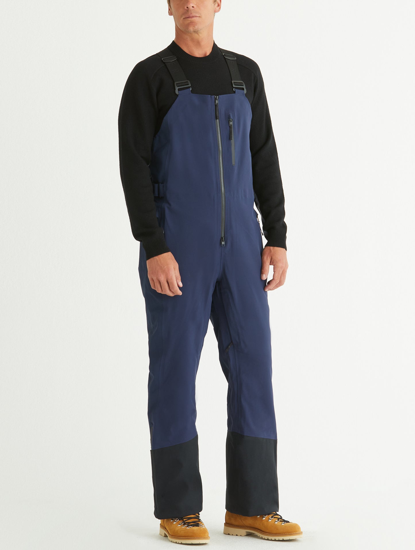 Front angled full-body view of man wearing Stealth Snow Bib in Nordic Navy blue from AETHER Apparel.
