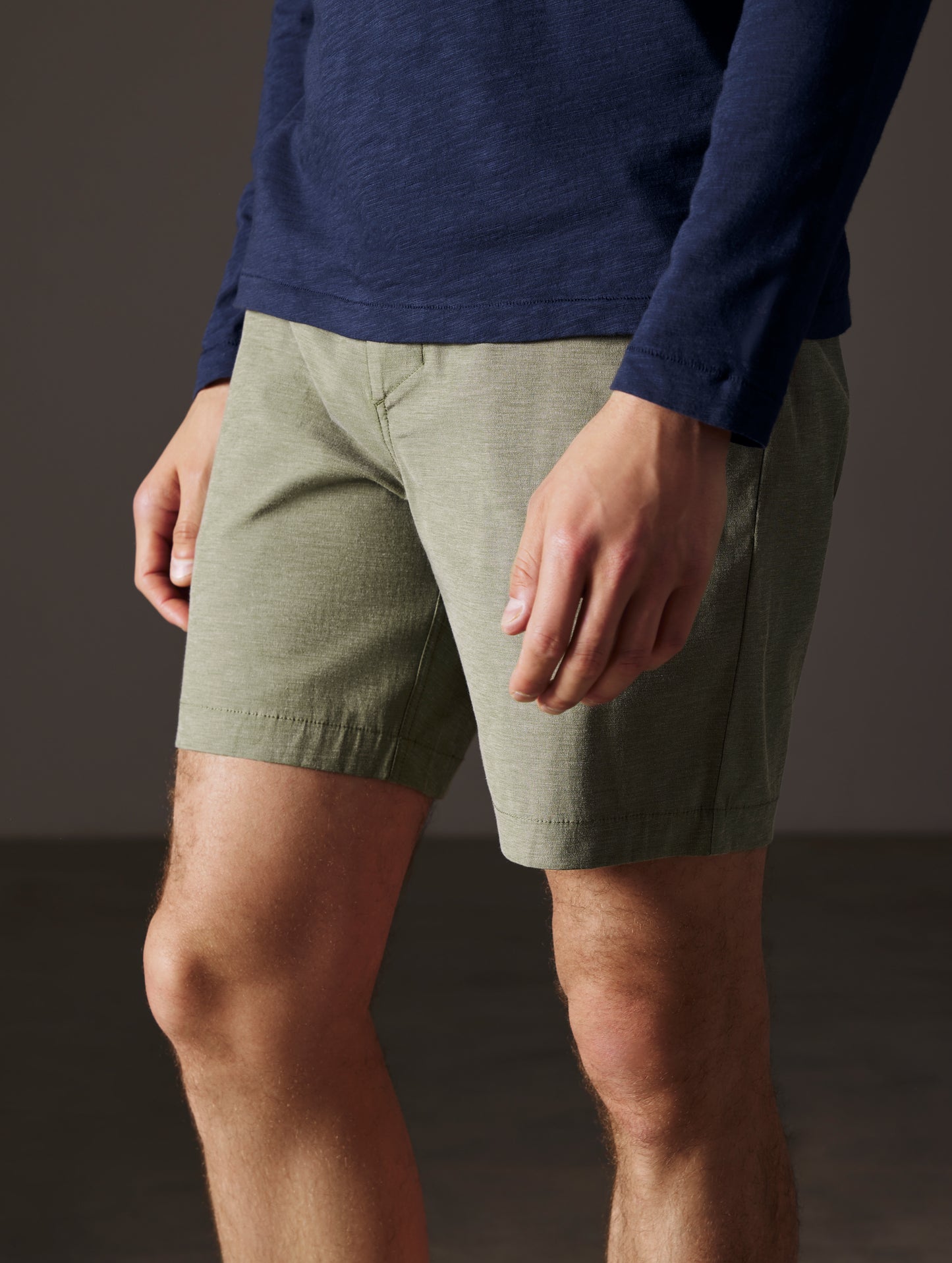 Front angled lower body view of man wearing Strand Hybrid Swim Short 7" in Command Green from AETHER Apparel.