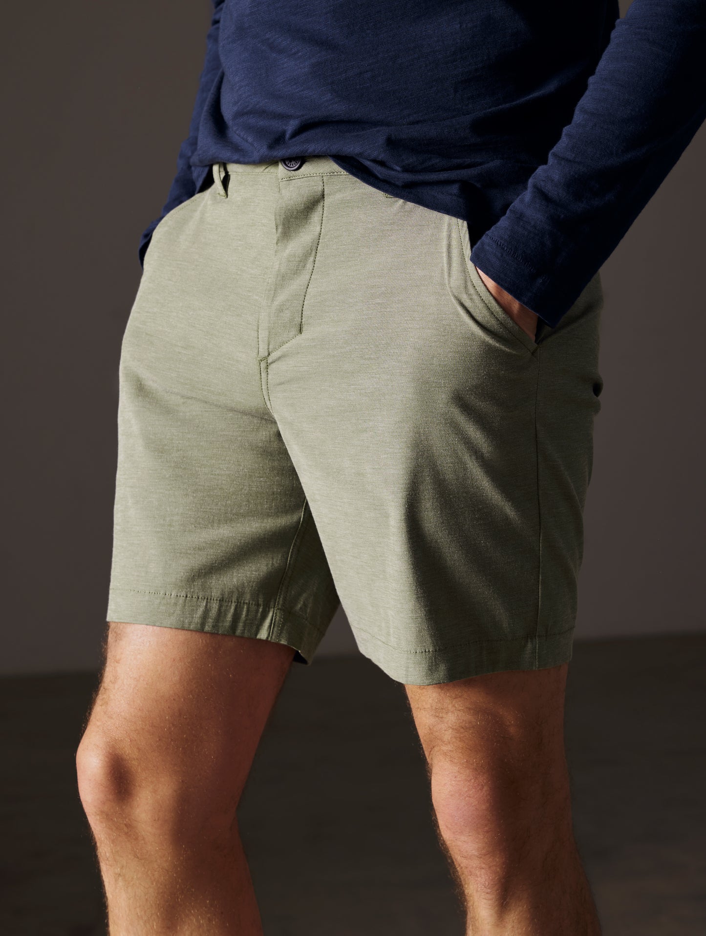 Front angled lower body view of man with hands in pockets wearing Strand Hybrid Swim Short 7" in Command Green from AETHER Apparel.