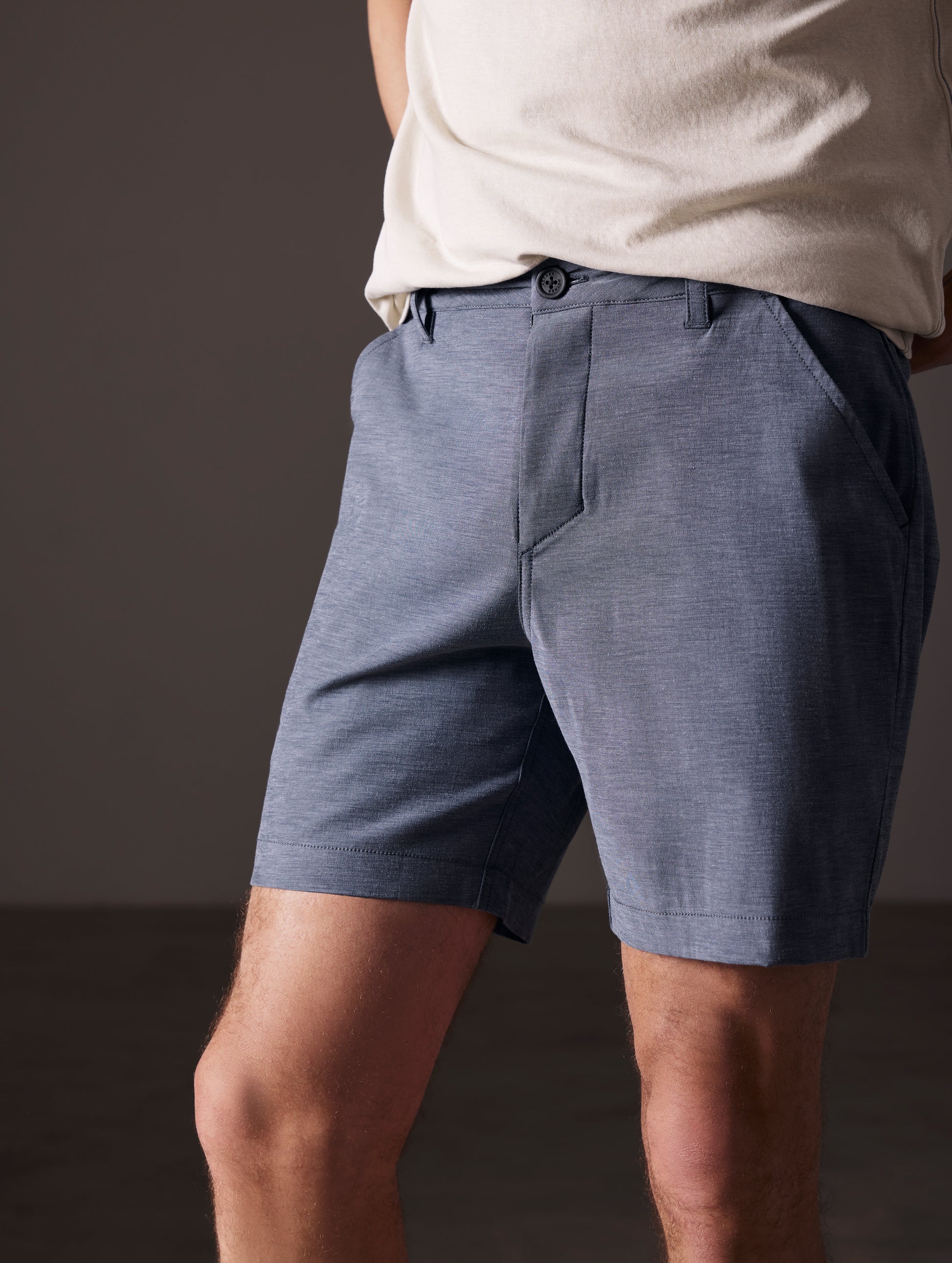 Front angled lower body view of man standing with bent knees wearing Strand Hybrid Swim Short 7" in Slate Heather from AETHER Apparel.