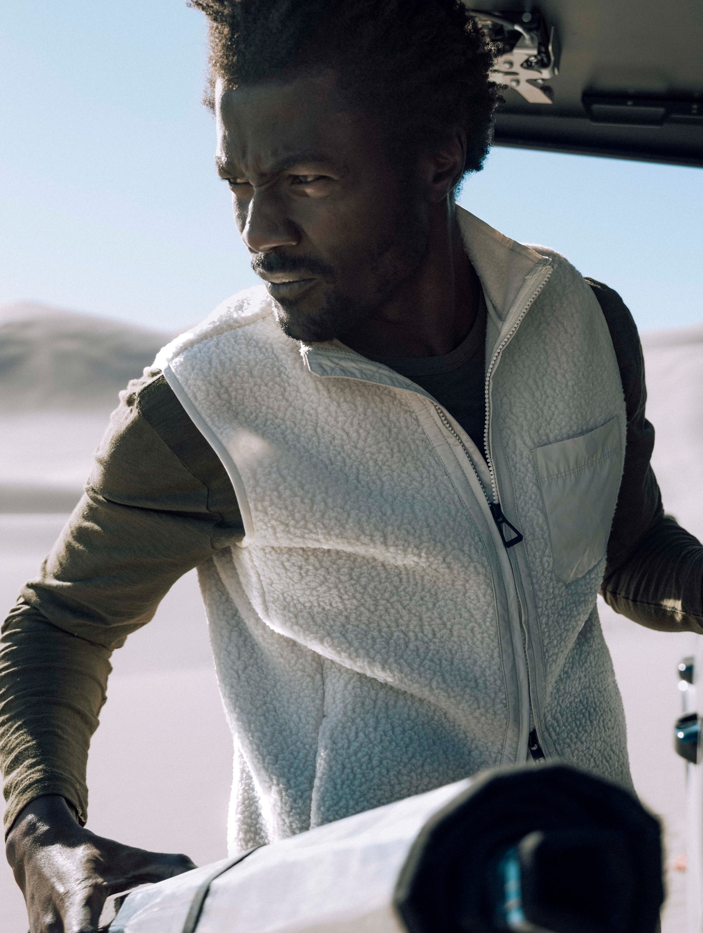 Outdoor lifestyle image of man wearing Walsh Vest in Bone white from AETHER Apparel.