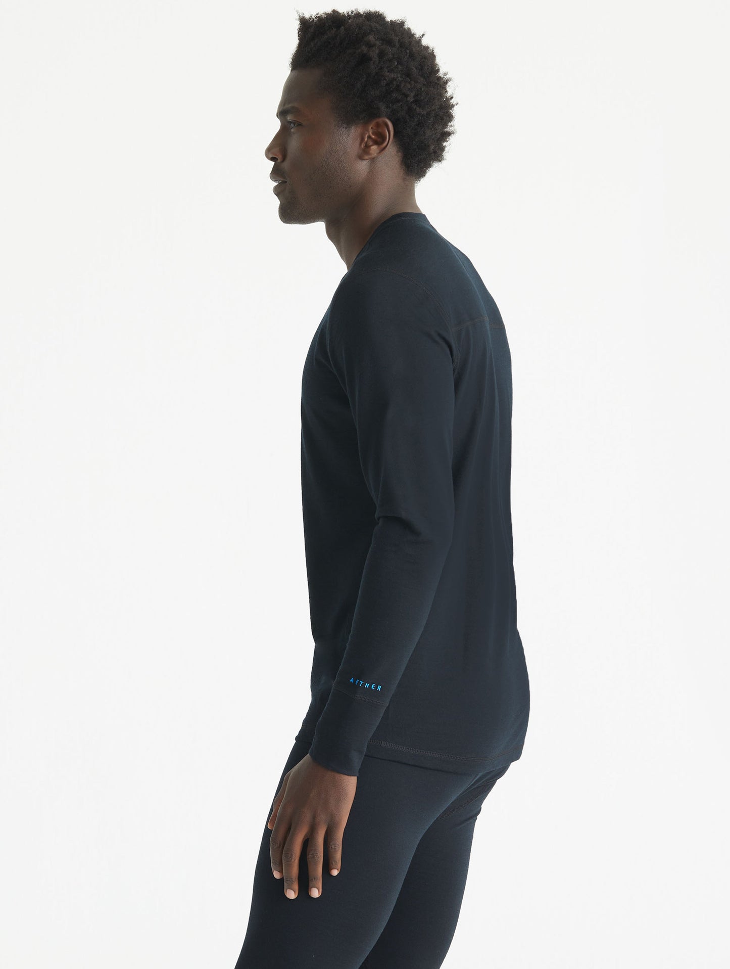Side profile body view of man wearing Premium Merino Base Layer Crew in Jet Black from AETHER Apparel.
