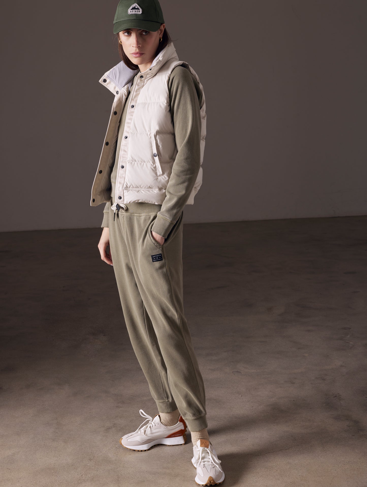 Full body view of woman wearing beige Anning insulated vest from AETHER Apparel.