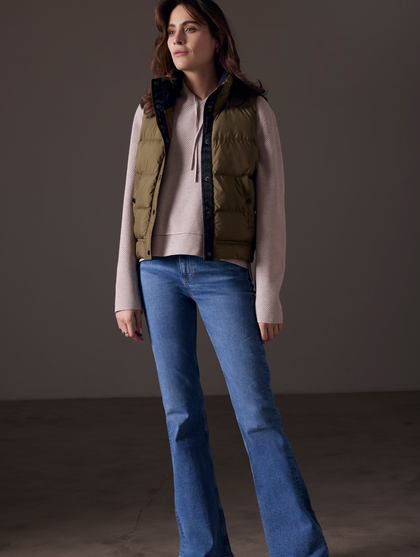 Full body view of woman wearing green Anning insulated vest from AETHER Apparel.