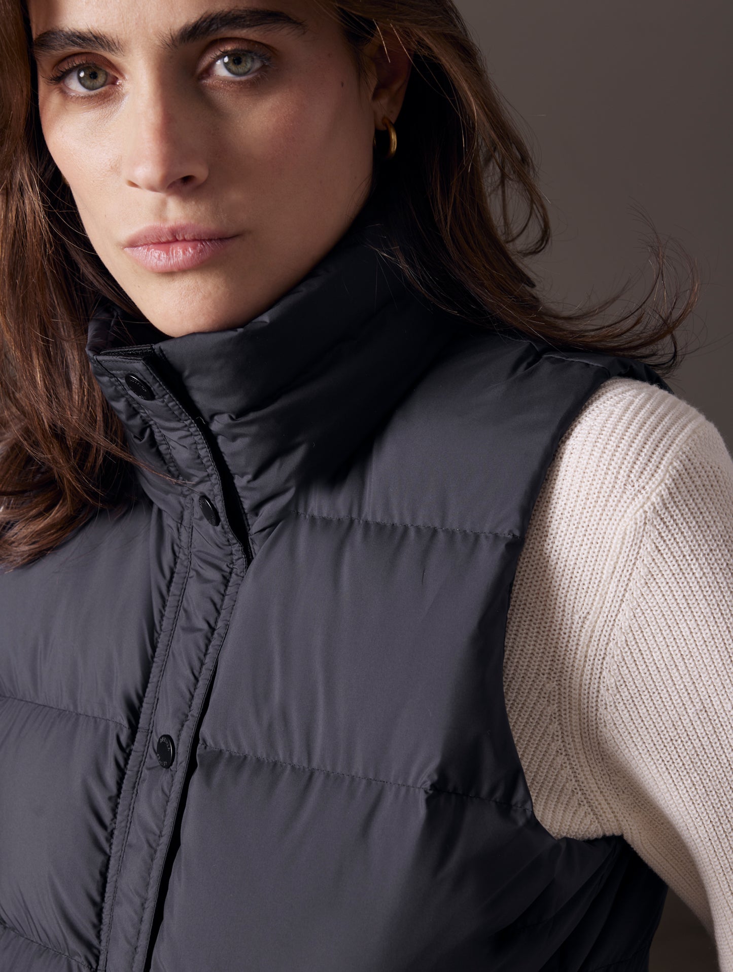Close-up view of woman wearing black Anning insulated vest from AETHER Apparel.
