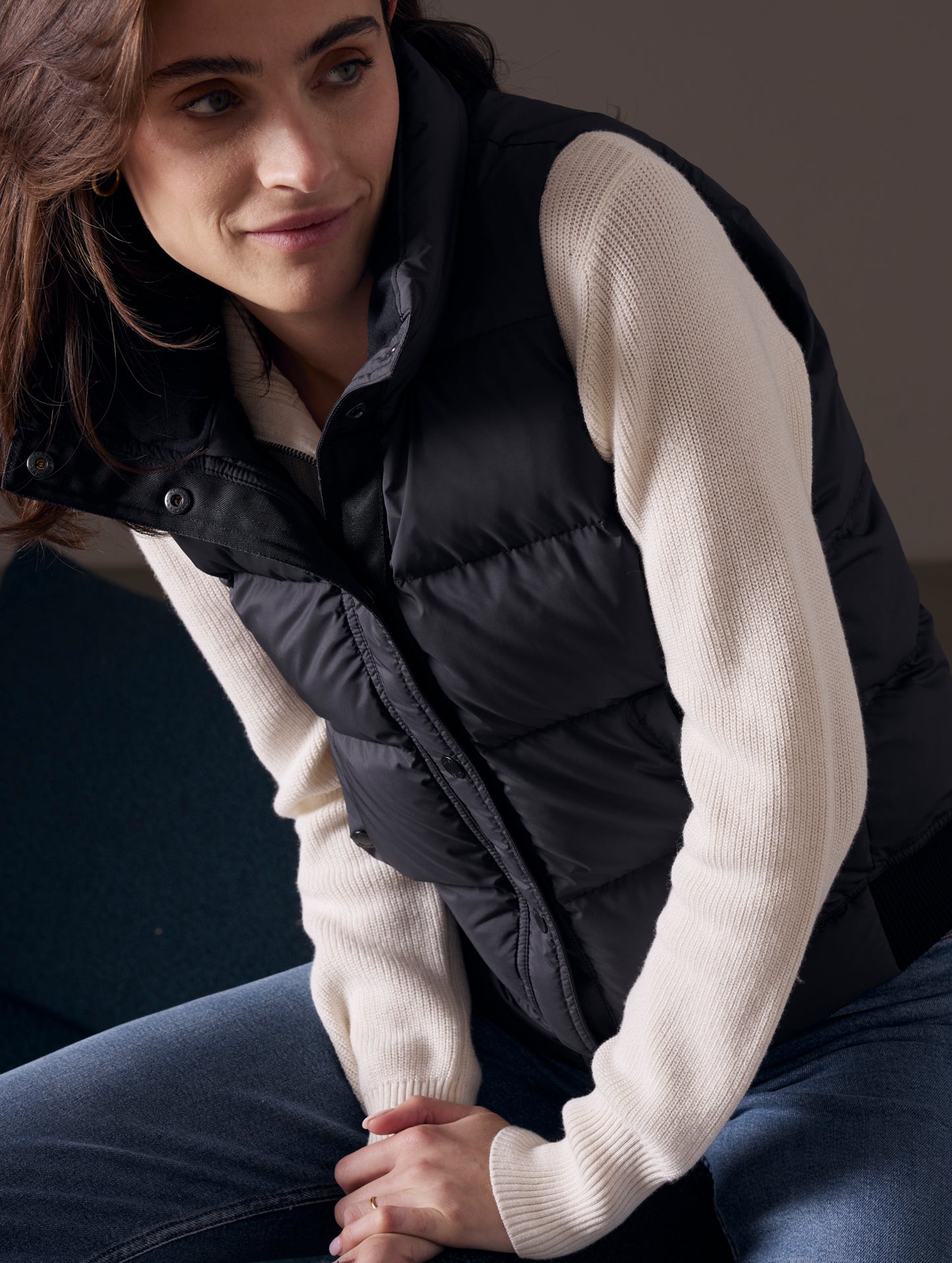 Woman sitting down wearing black Anning insulated vest from AETHER Apparel.