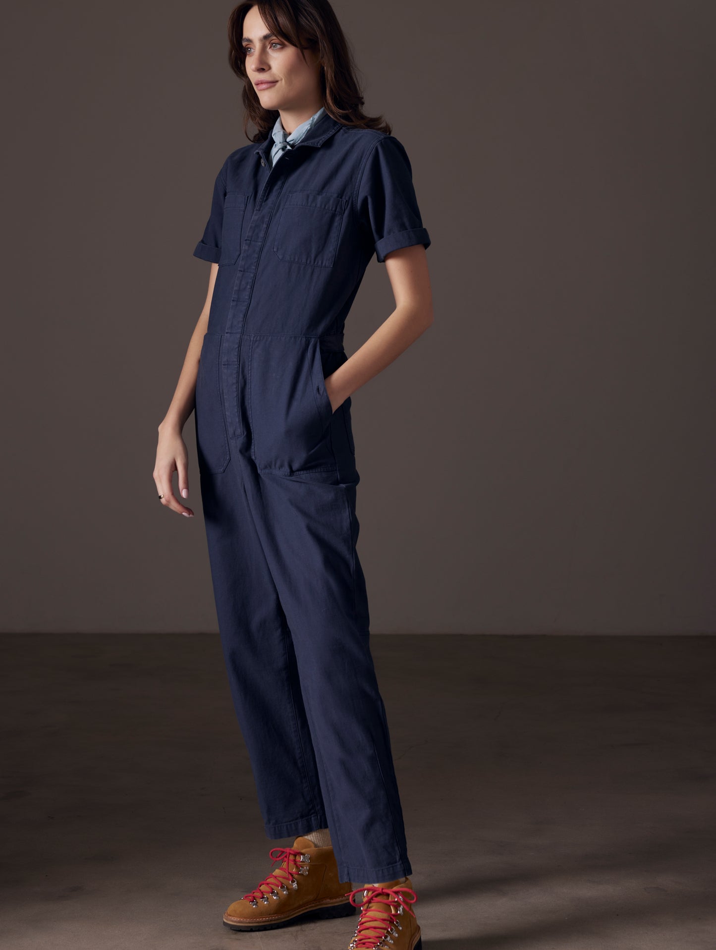 Front angled full-body view of woman wearing Bard Jumpsuit in Total Eclipse dark blue from AETHER Apparel.