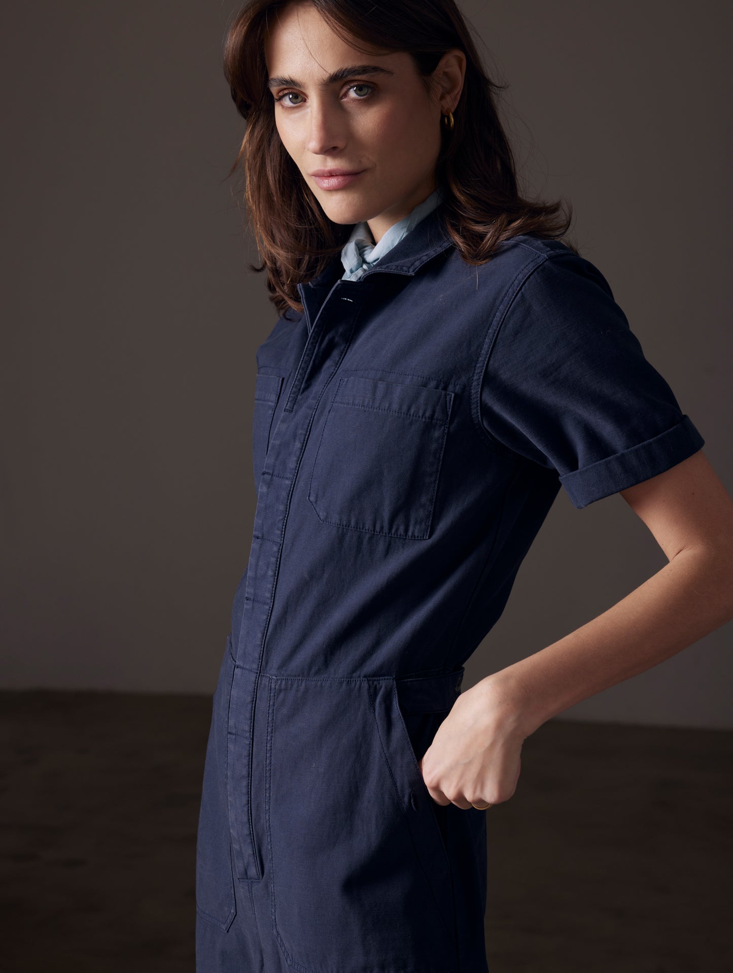 Front angled view of woman wearing Bard Jumpsuit in Total Eclipse dark blue from AETHER Apparel.