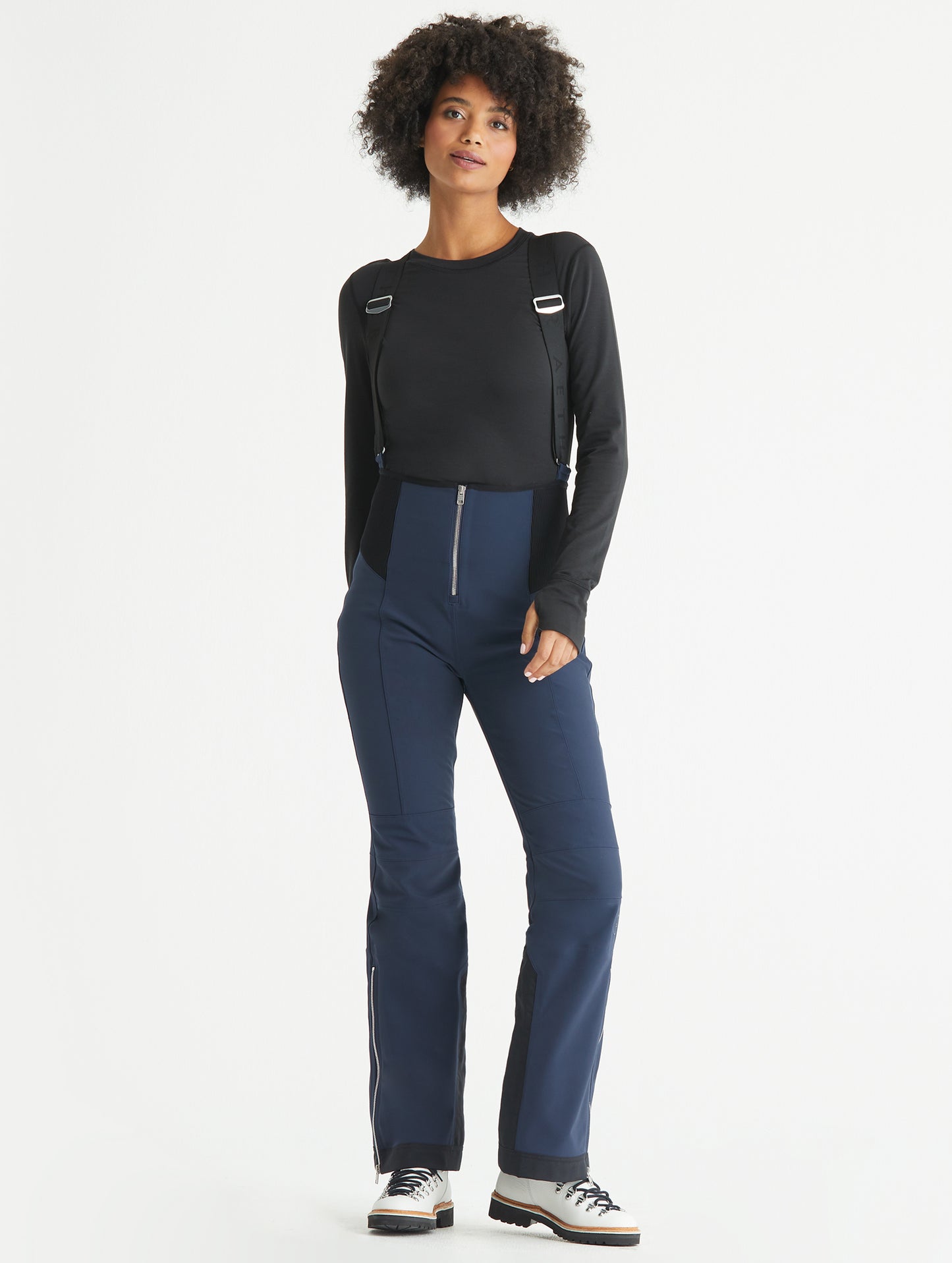 Front full-body view of woman wearing Descent Snow Bib 2.0 in Total Eclipse dark blue from AETHER Apparel.