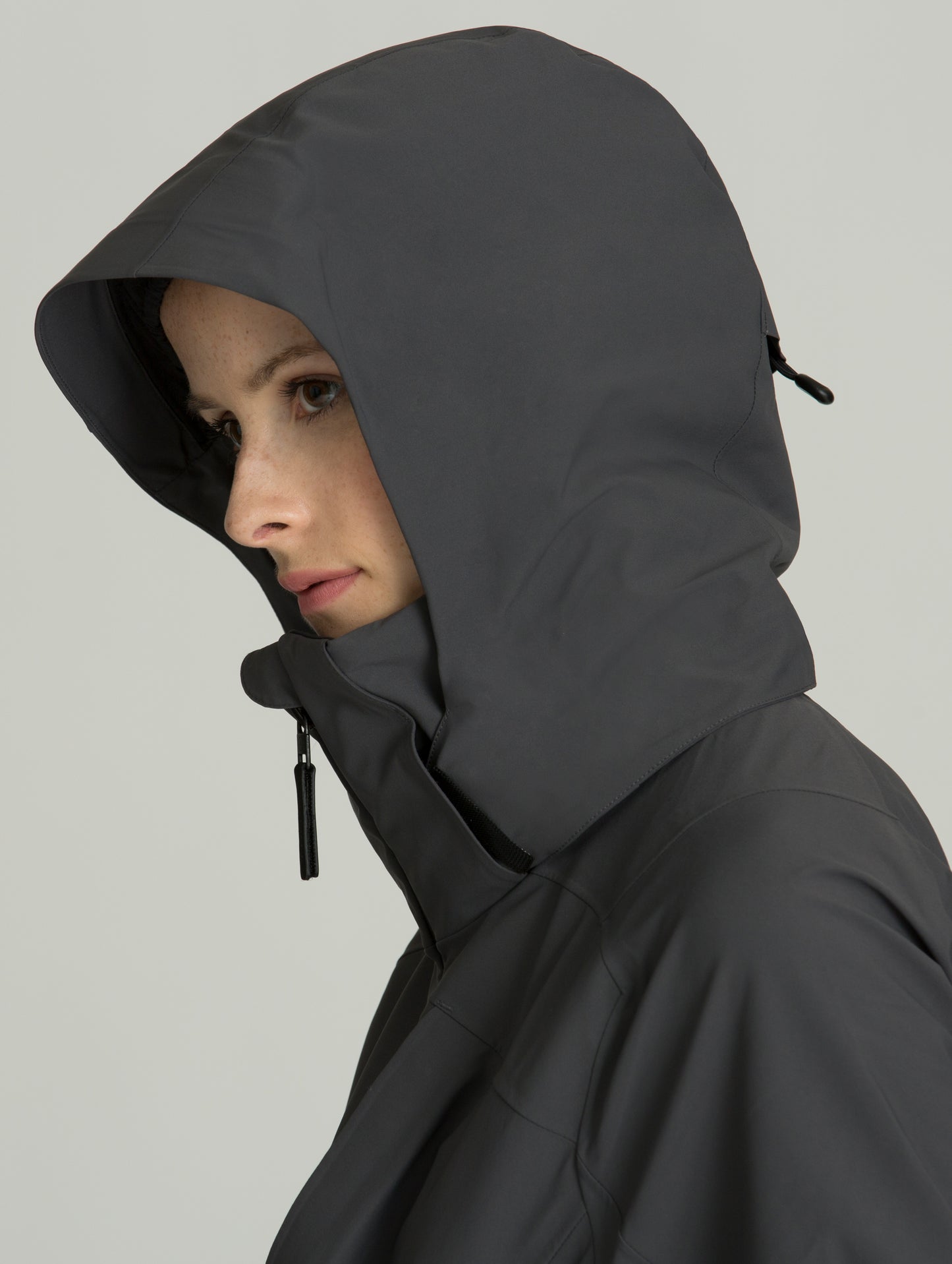 Woman wearing dark grey Cirque Shell from AETHER Apparel displaying hood and collar.