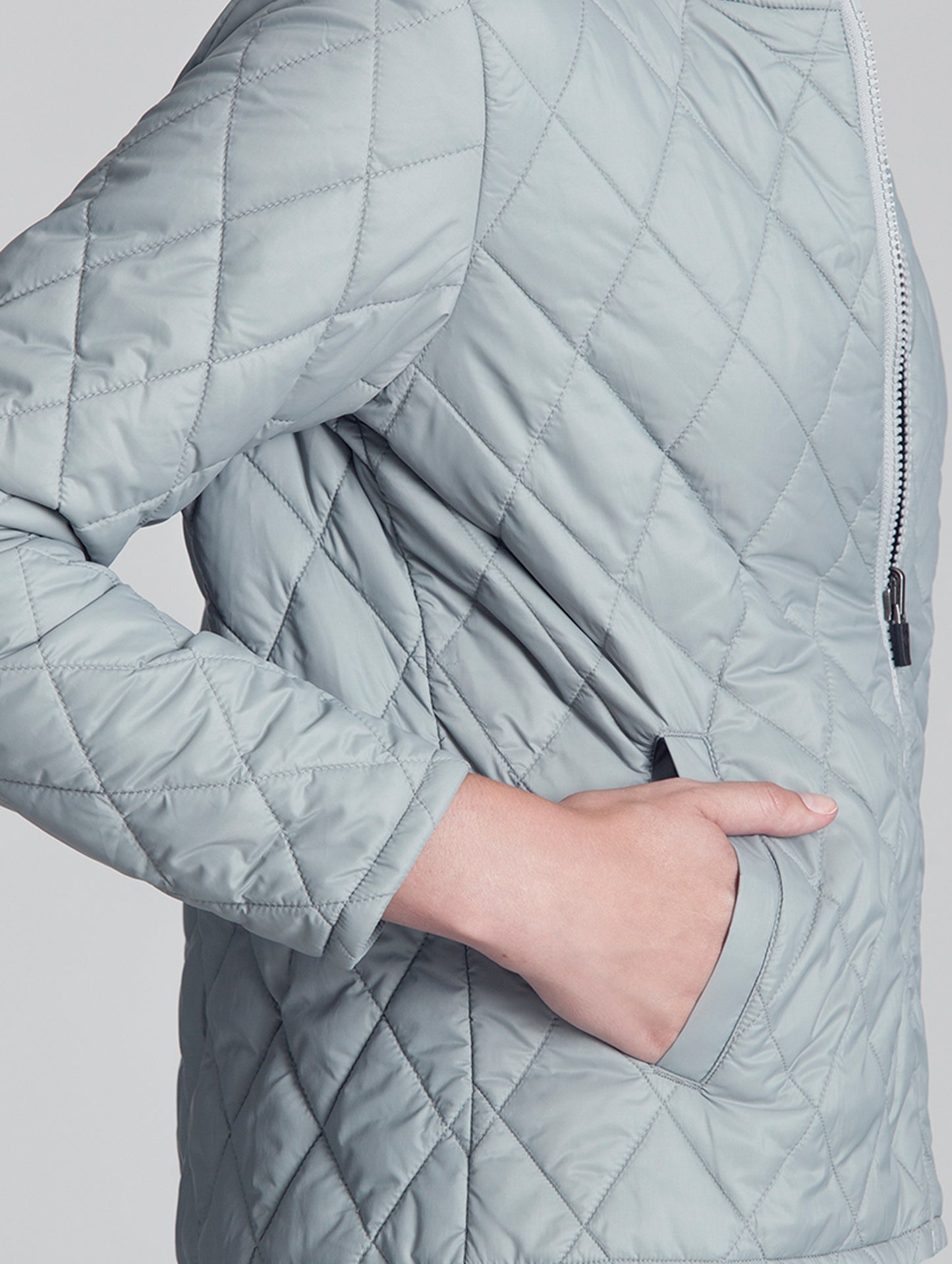 Woman wearing light grey liner of Crosby Jacket from AETHER Apparel, displaying left hand pocket.