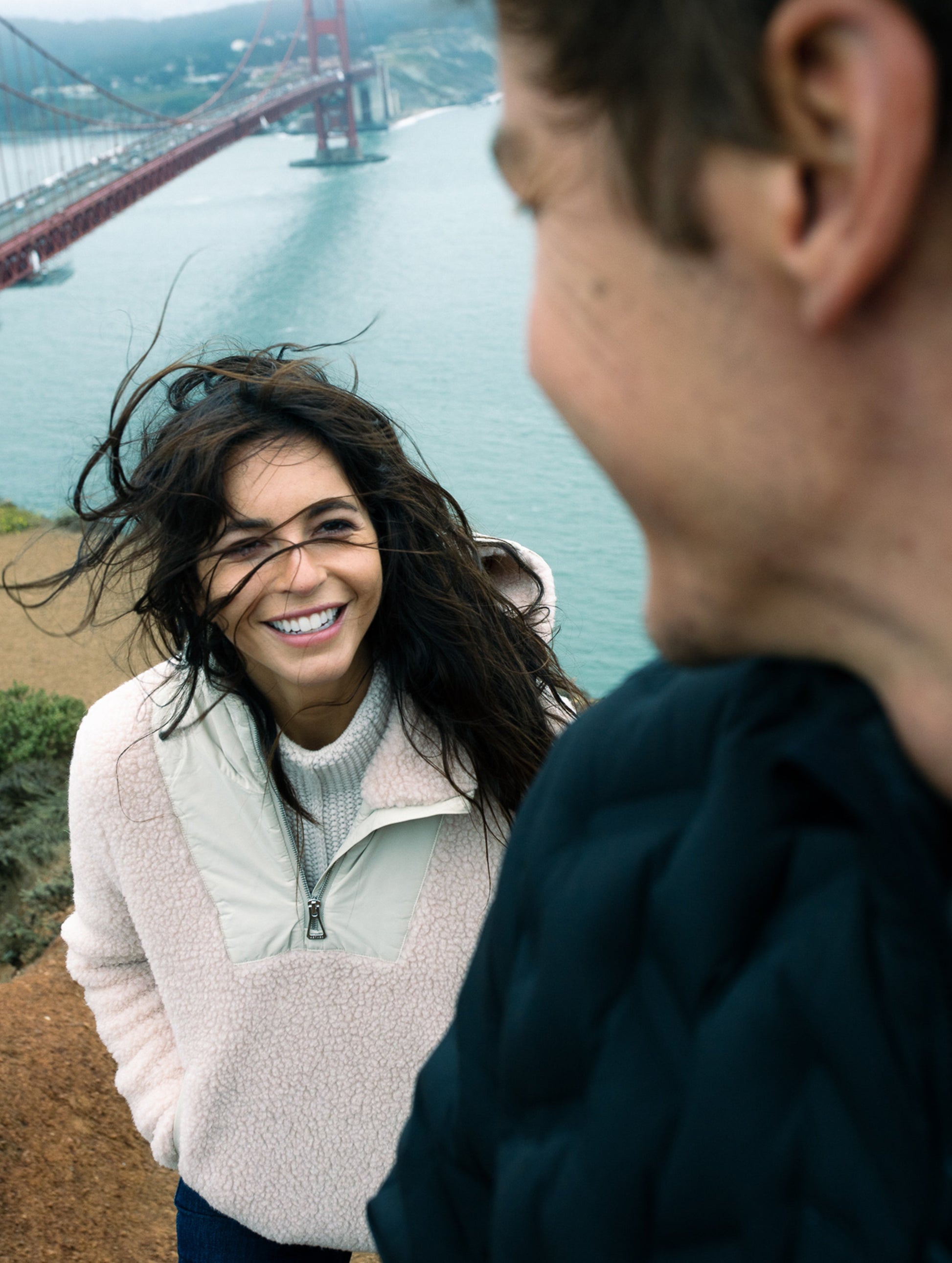 Woman outdoors wearing pink Narrow Pullover from AETHER Apparel looking at man wearing black Rex Down Jacket.