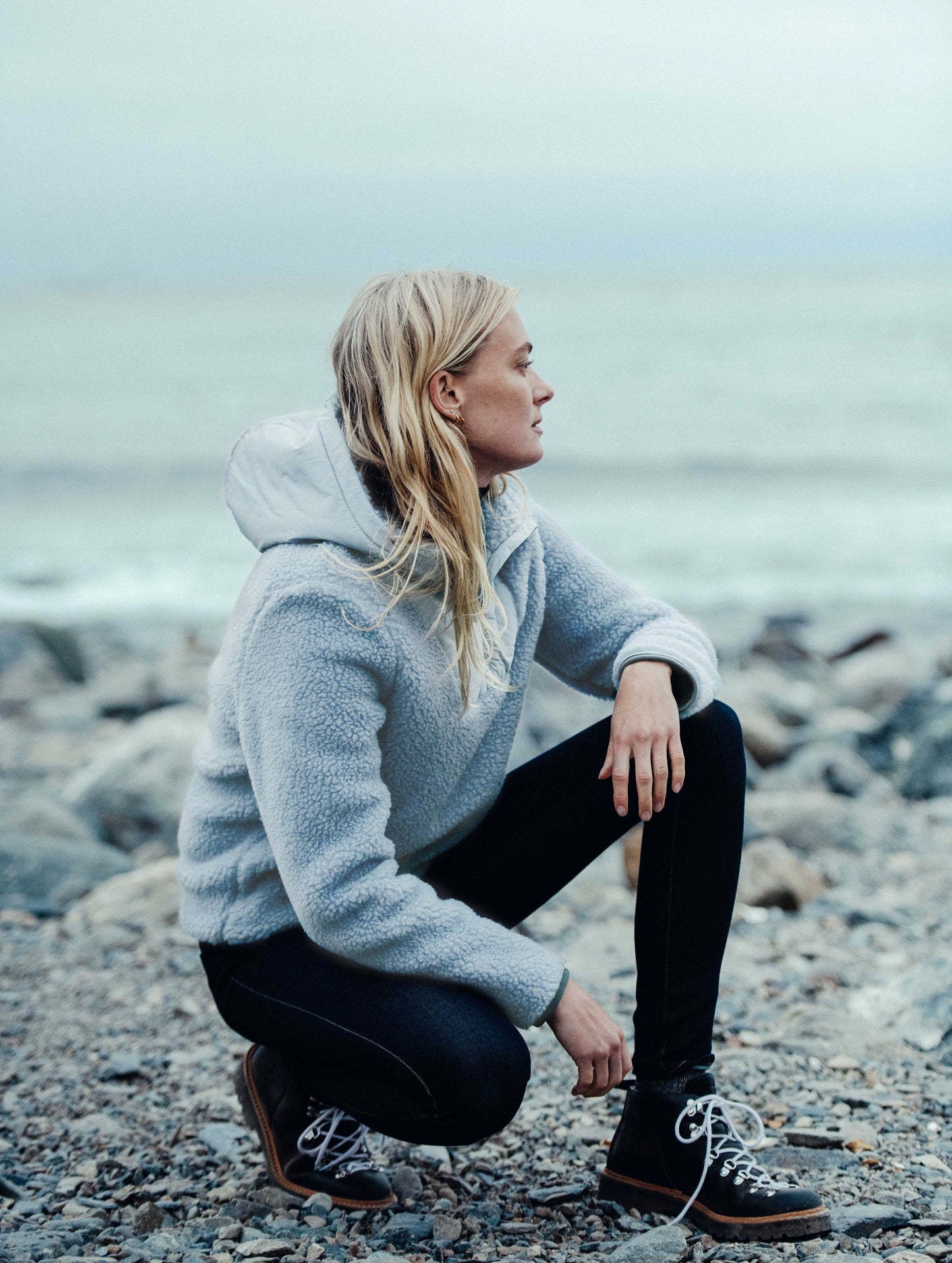 Side view of woman outdoors wearing blue Narrow Pullover from AETHER Apparel.