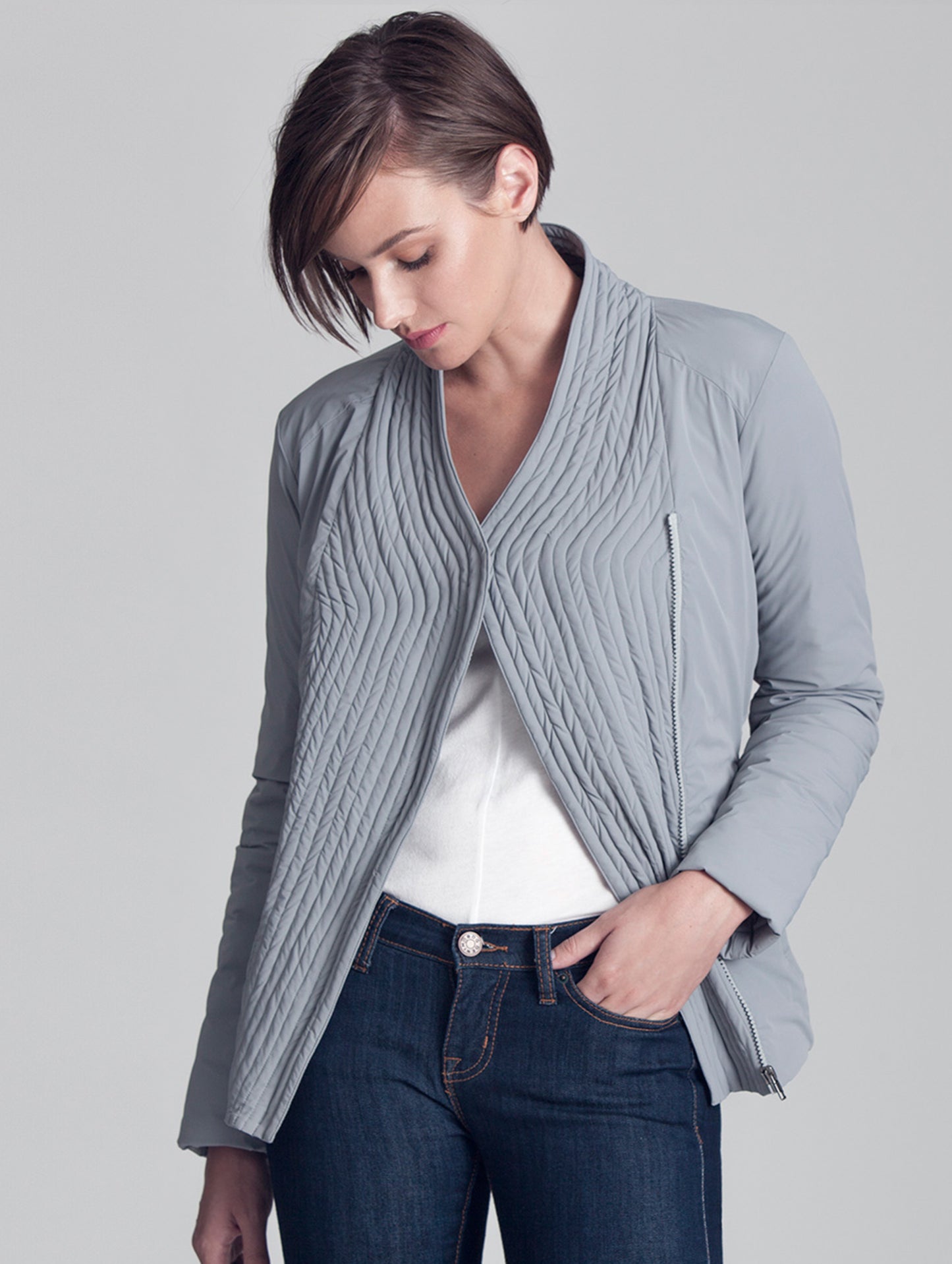 Woman wearing opened grey Passport Jacket from AETHER Apparel.