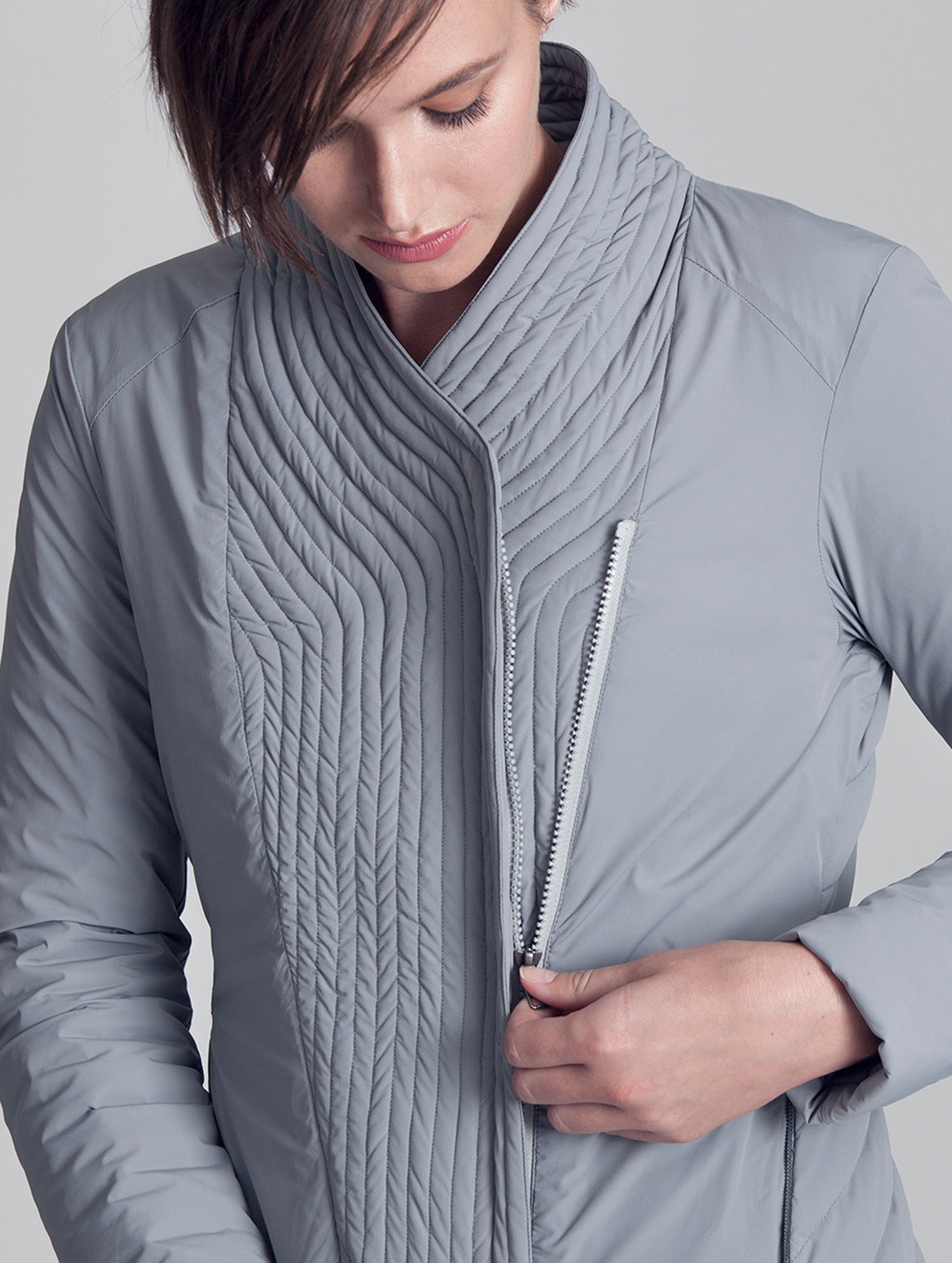 Close view of woman wearing grey Passport Jacket from AETHER Apparel, displaying front zipper.